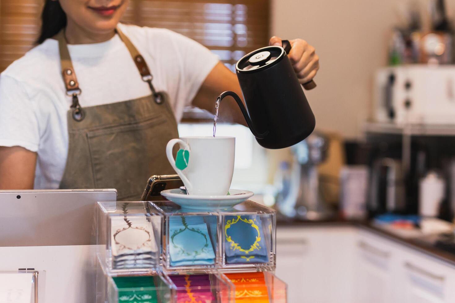 Woman with apron pouring hot water into a mug make herbal tea. photo