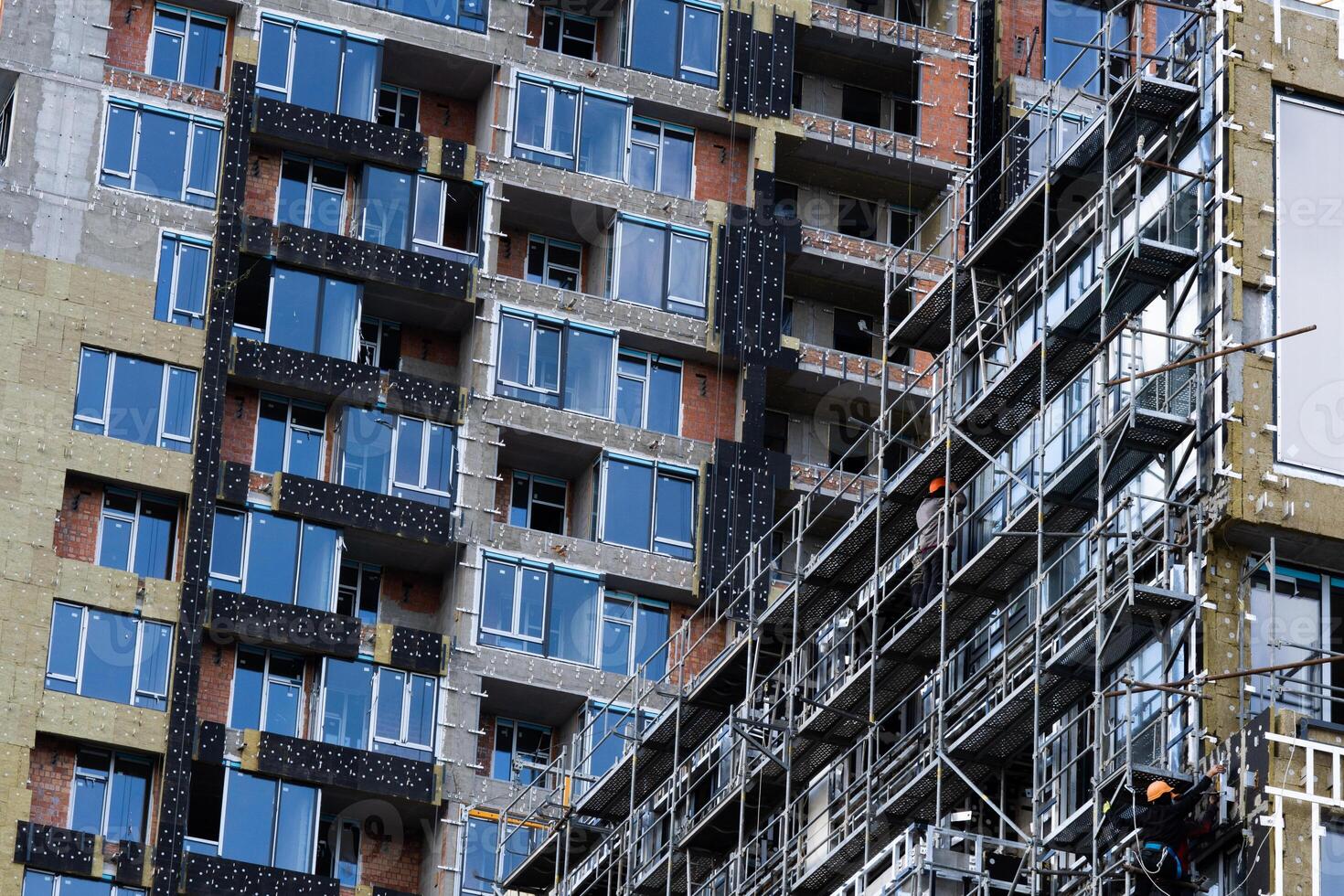 Construction of scaffolding and installation of glass facade panels against the backdrop of a new building photo