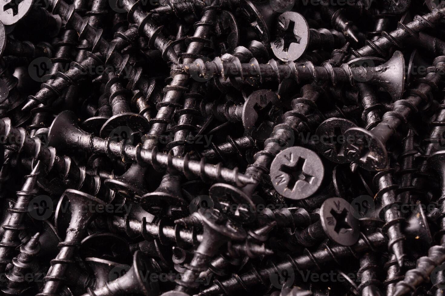 Abstract background pile of shiny black screws. photo