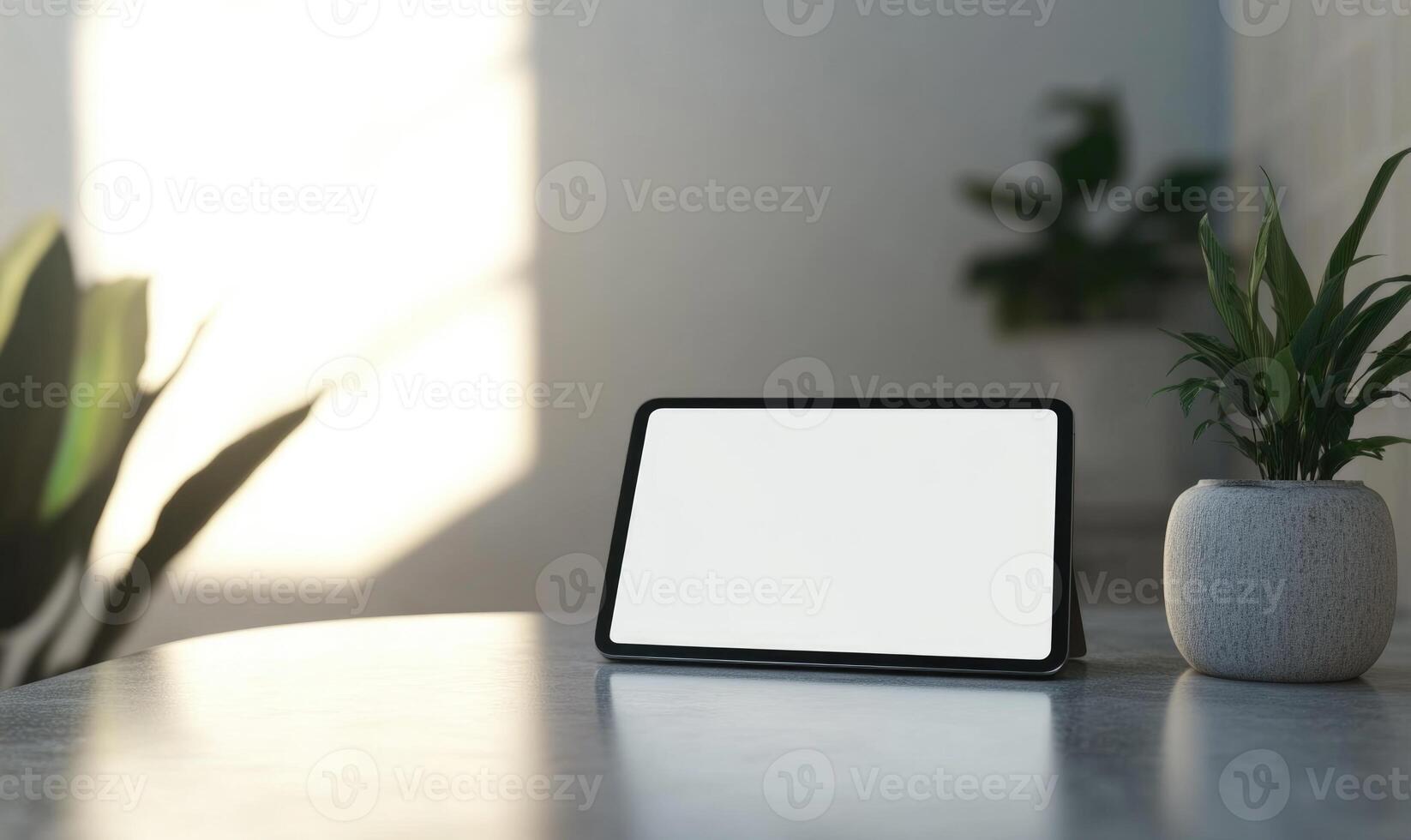 A tablet sits on a table next to a potted plant photo