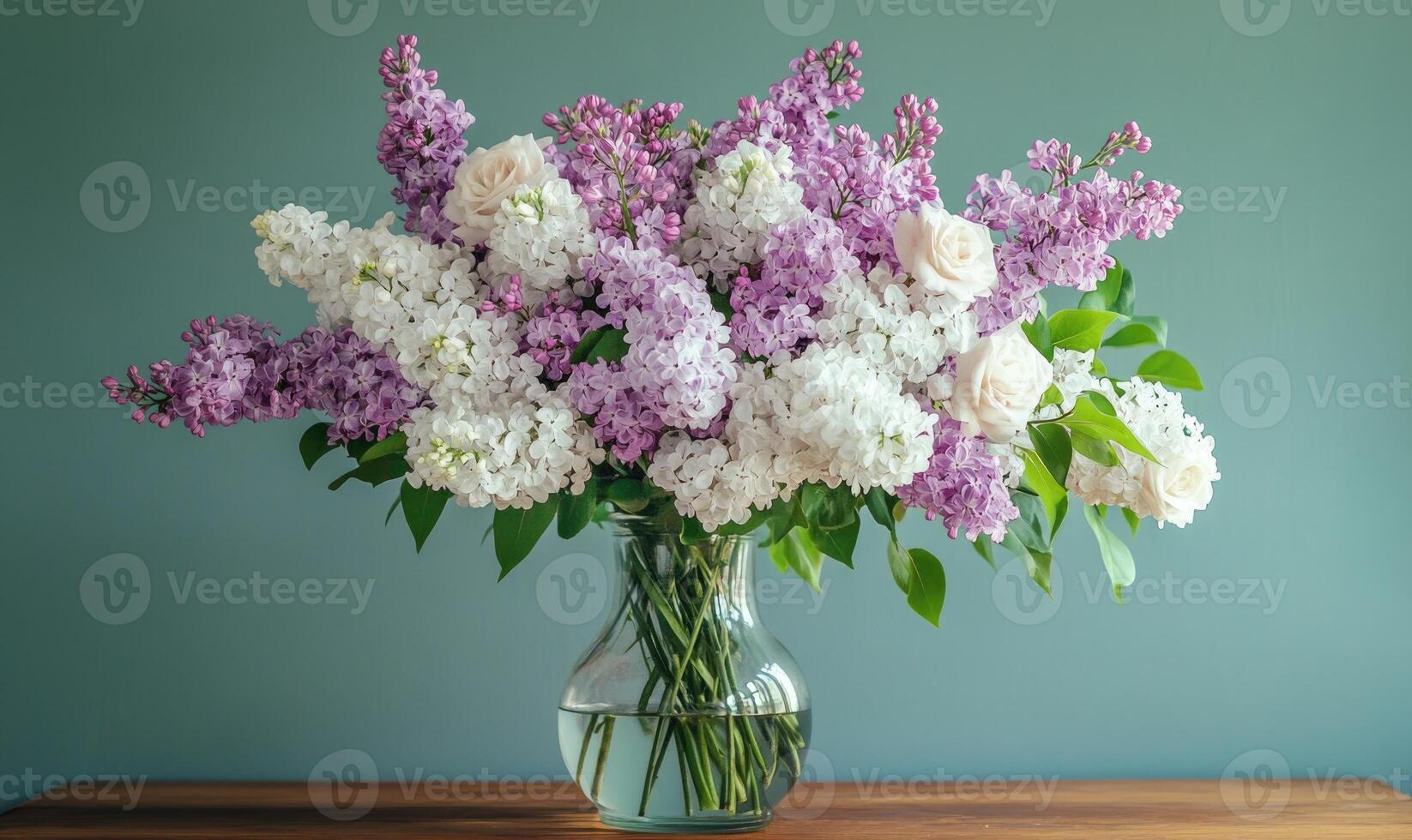 A vase filled with purple and white flowers sits on a wooden table photo