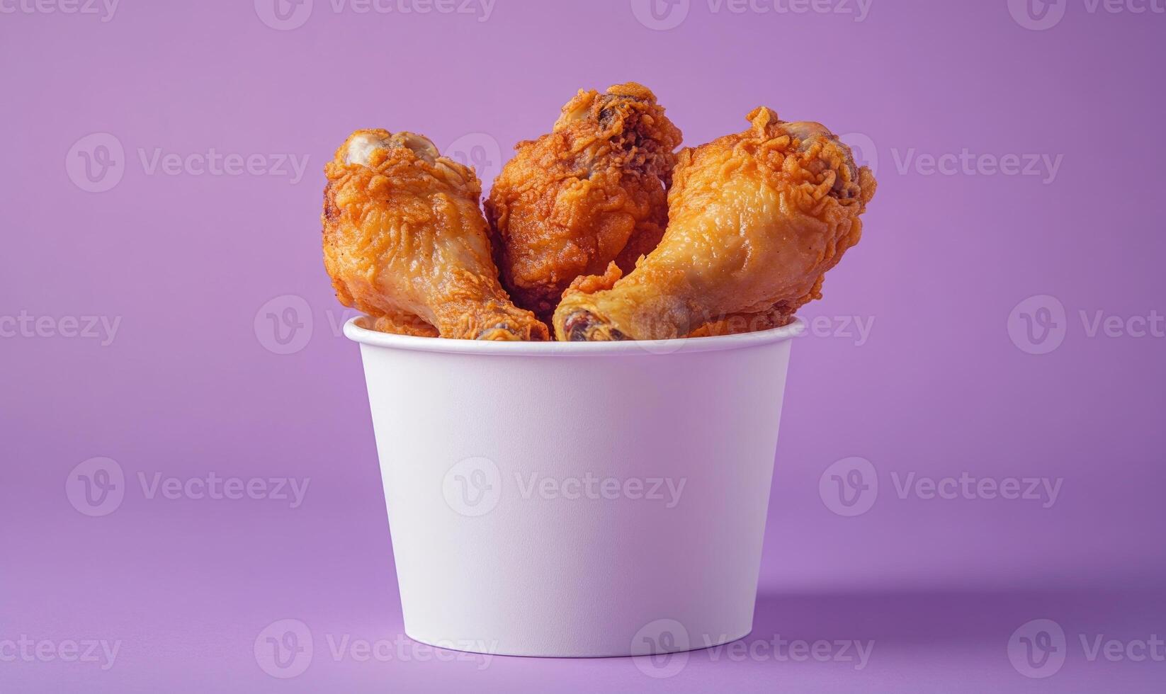 A white paper cup filled with three pieces of fried chicken photo