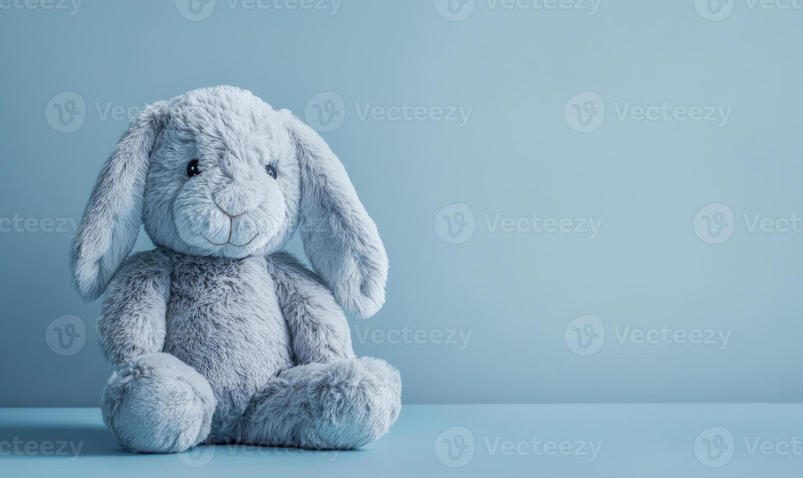 A stuffed rabbit is sitting on a blue table photo