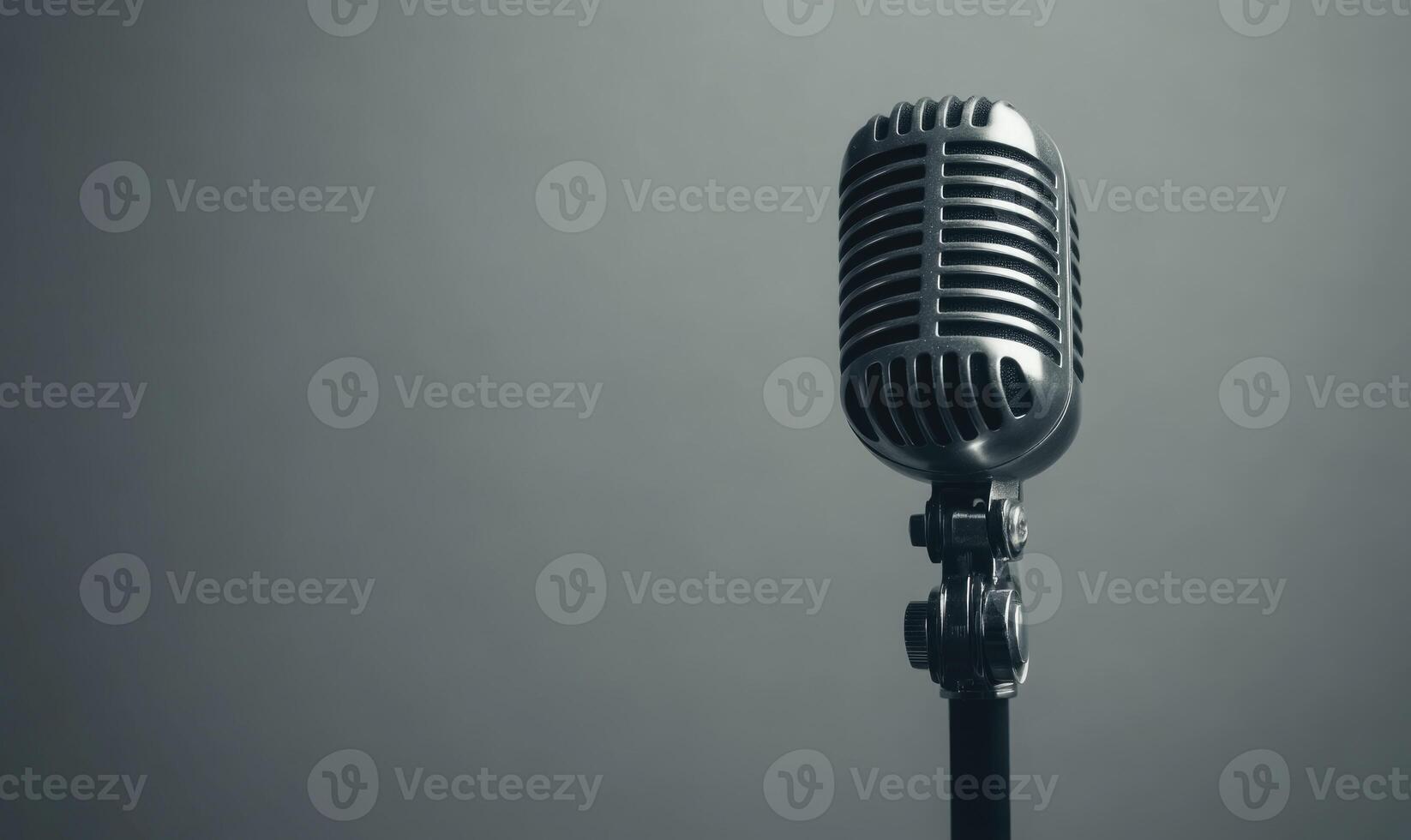 A microphone is on a stand in front of a grey background photo