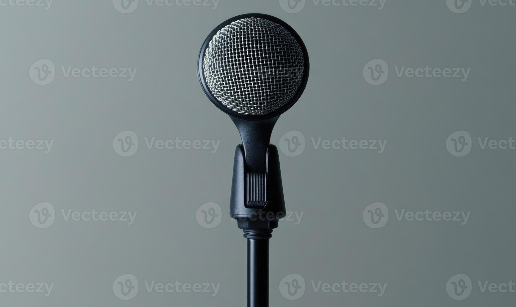 A microphone is standing upright on a grey background photo