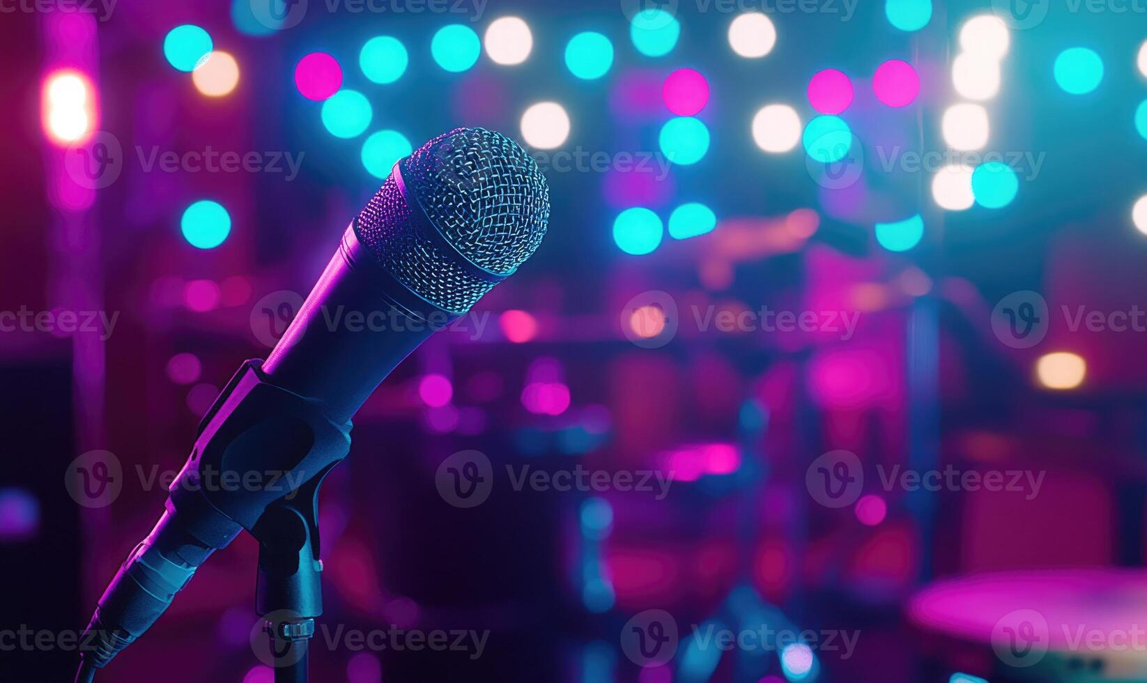 A microphone is on a stand in front of a drum set photo