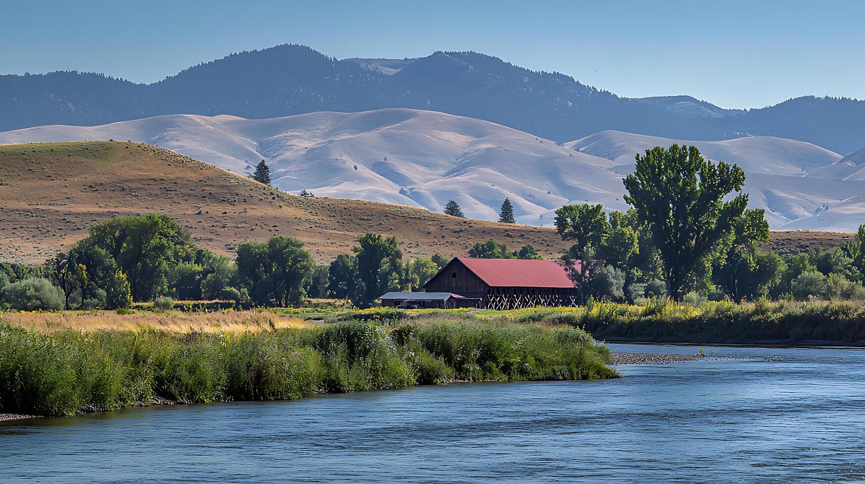 Serene Montana Barn by the River with Mountain Views. A picturesque landscape photograph showcasing a rustic barn nestled beside a calm river, set against the backdrop of majestic mountains. photo