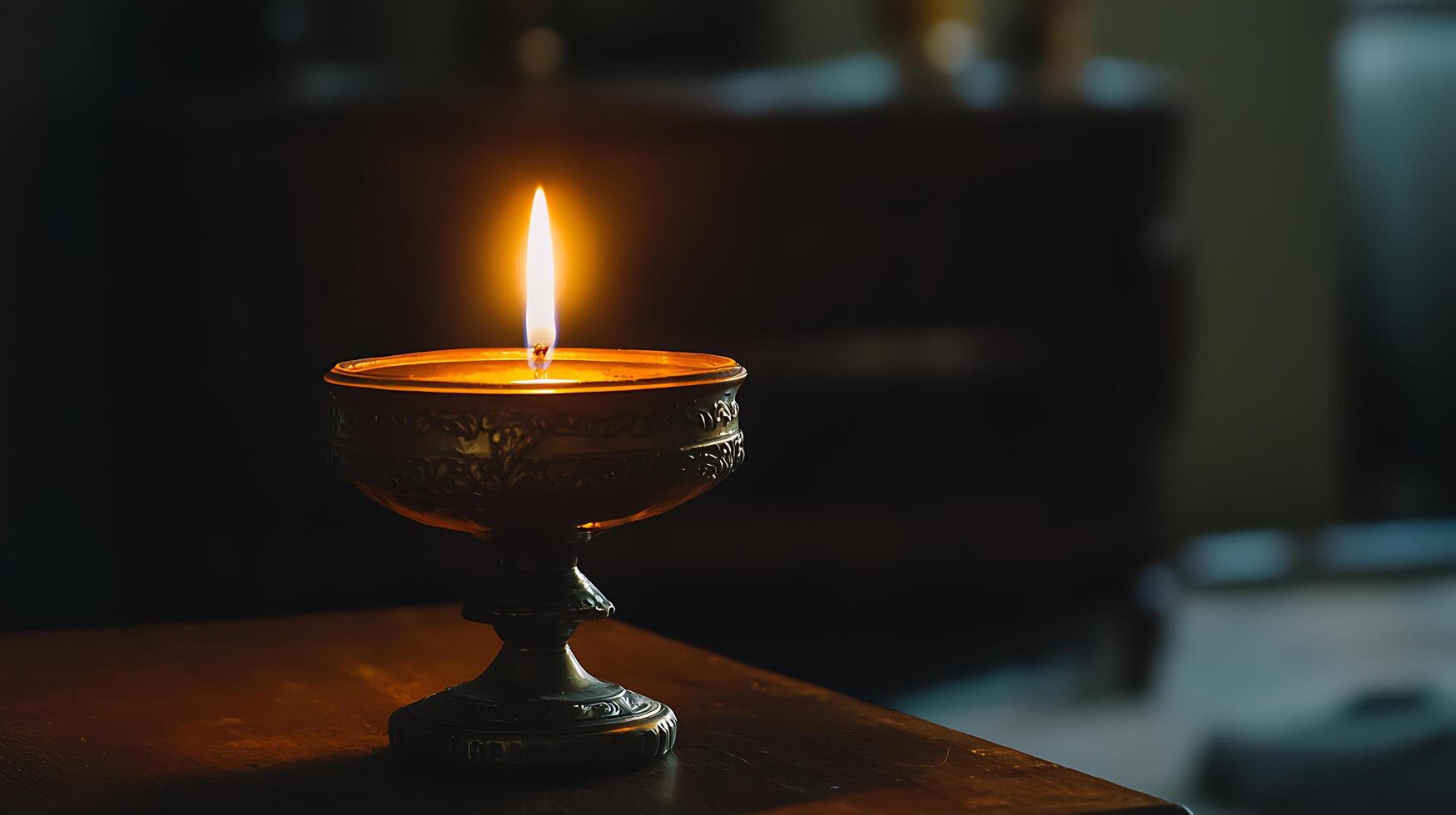 Ornate Candle Holder with Lit Candle on Dark Wooden Surface. photo