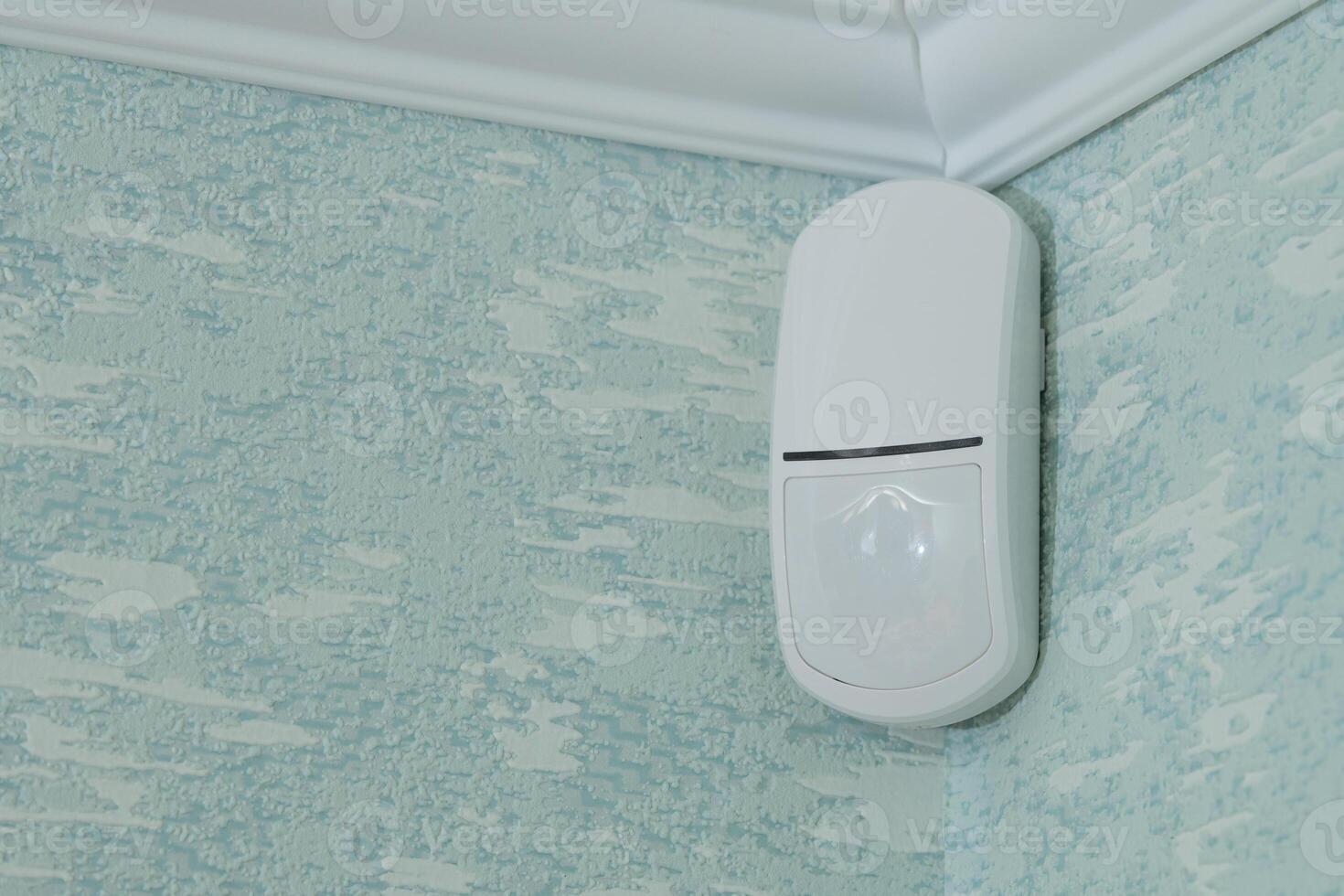Modern white motion sensor on the wall in the room. photo