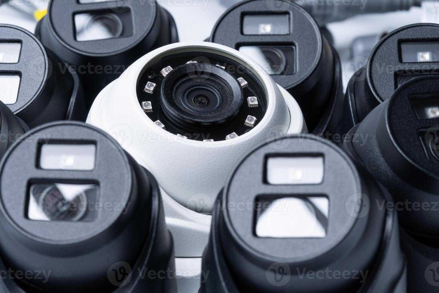 close-up of a white security camera surrounded by black cameras photo