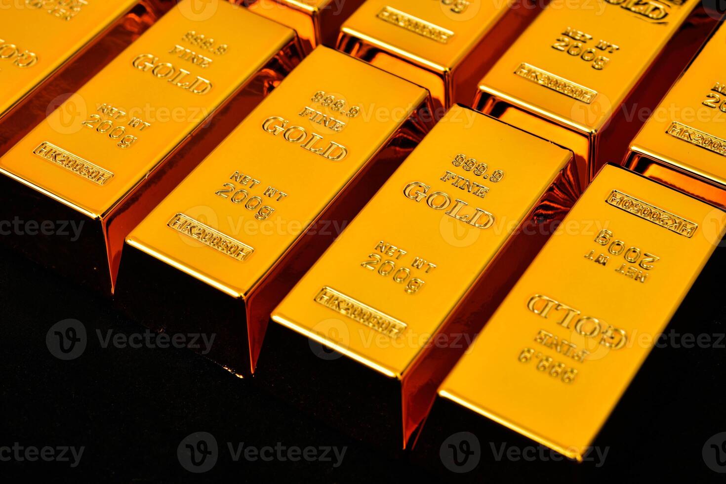 gold bars are stacked in rows on a black surface photo