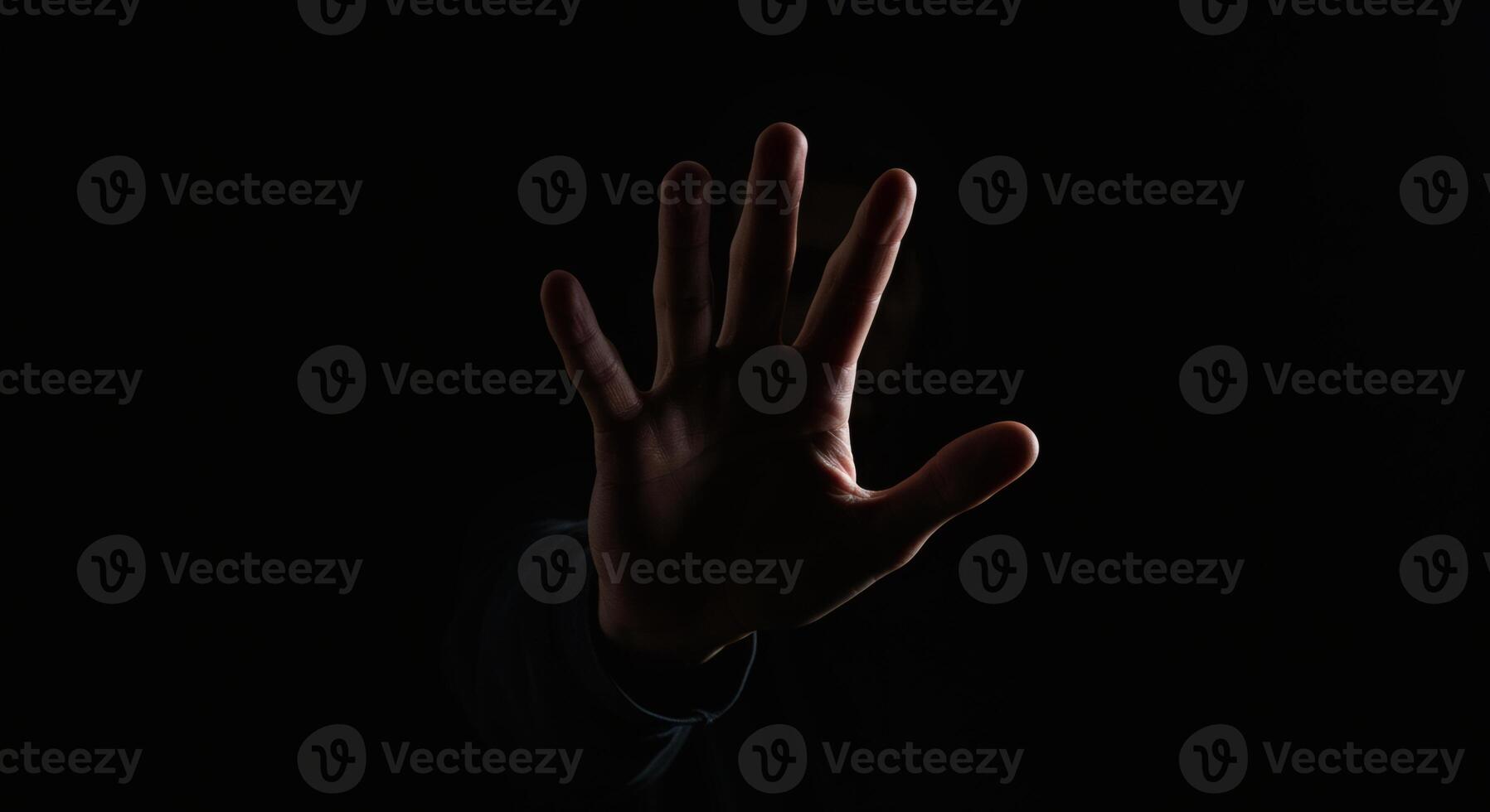 hand emerging from darkness, palm outstretched in a stop gesture, dramatically lit, conveying refusal or warning. photo