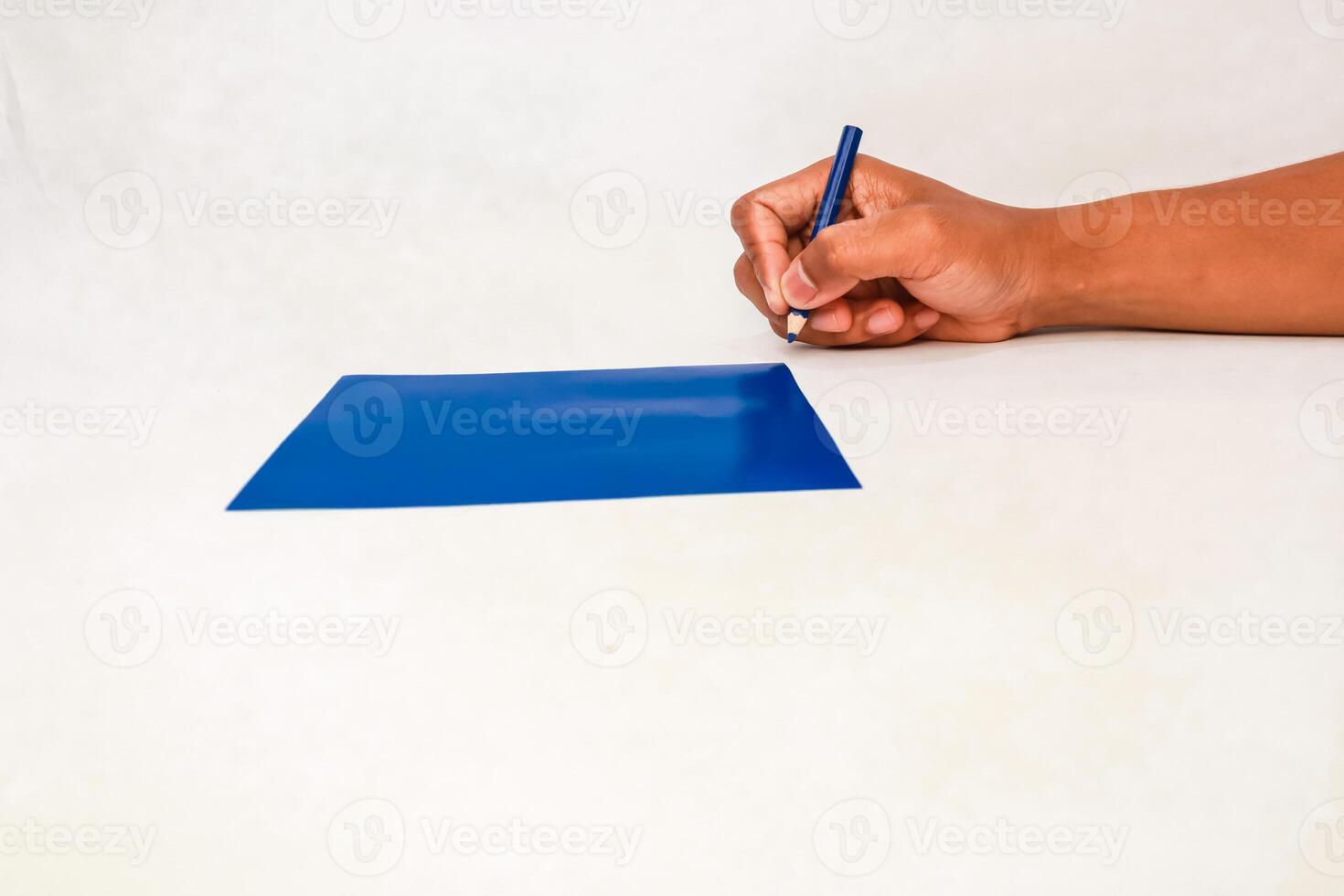 Writing on a blue surface with a pencil on a white background with human hand photo
