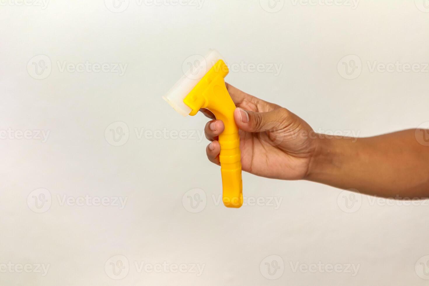 Close-up of Hand Holding Yellow Squeegee Tool for Cleaning Glass Windows and Surfaces photo