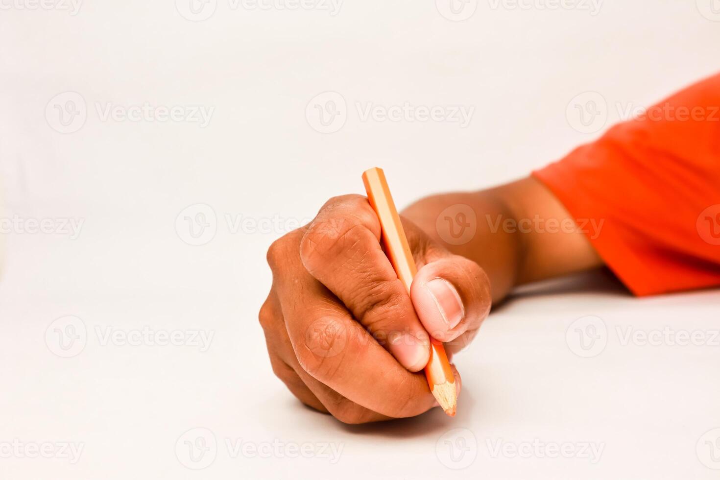 Close-up of a dark-skinned hand holding a pencil, creating, drawing or writing on a clean white surface photo