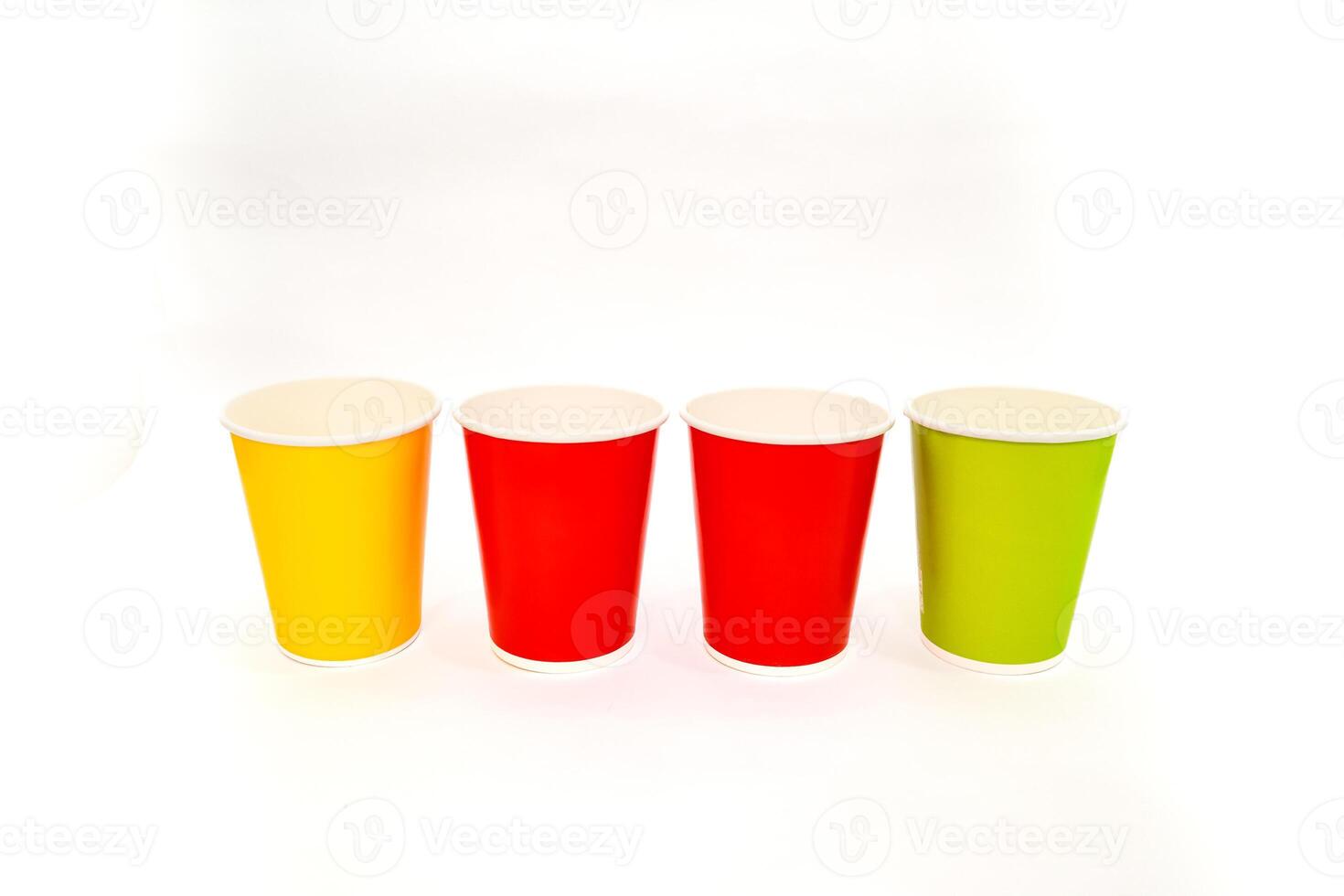 Four colorful paper cups standing in a row on a plain white background display. Isolated photo