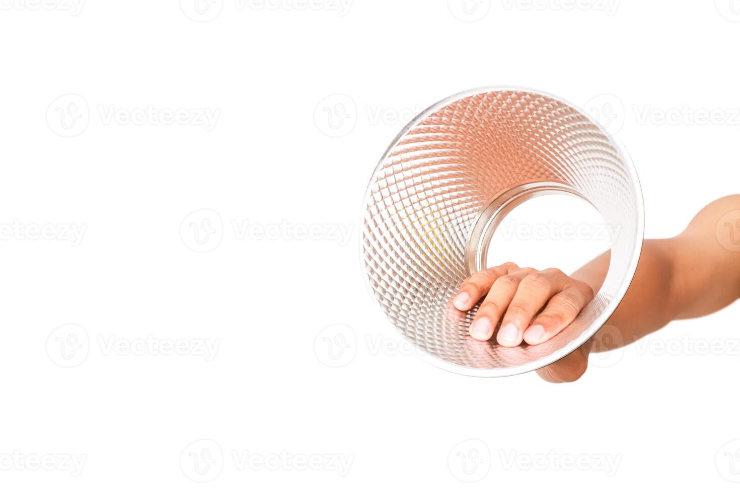 A hand holds a clear textured plastic ring against a white background in studio lighting photo