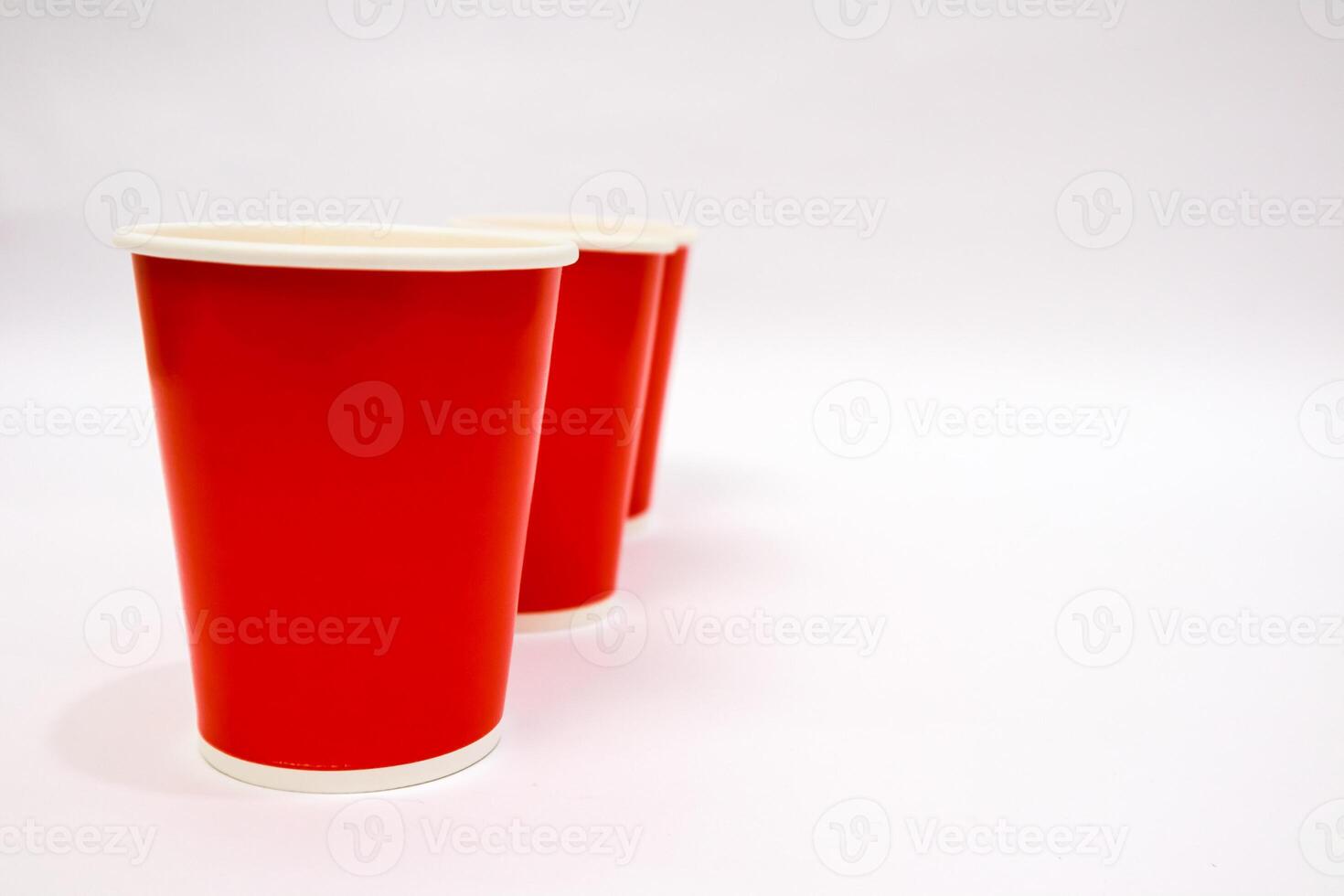 Three red disposable cups lined up against a plain white background with copy space photo