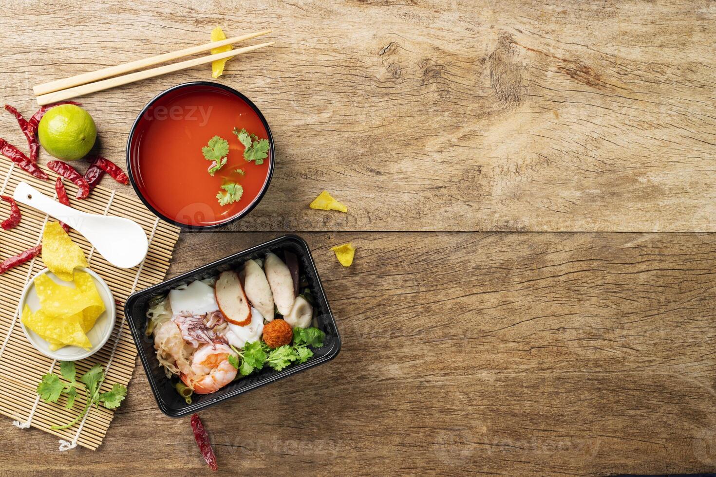 Noodles with shrimp and squid on a wooden tabletop view. Food packaging with plastic material cups. photo