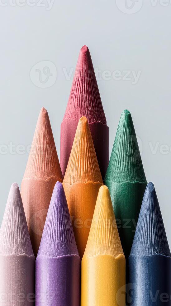 Colored crayon points arranged closely on gray surface. Vivid hues show details of tips. Row of art supplies points upward. Beautiful texture. photo