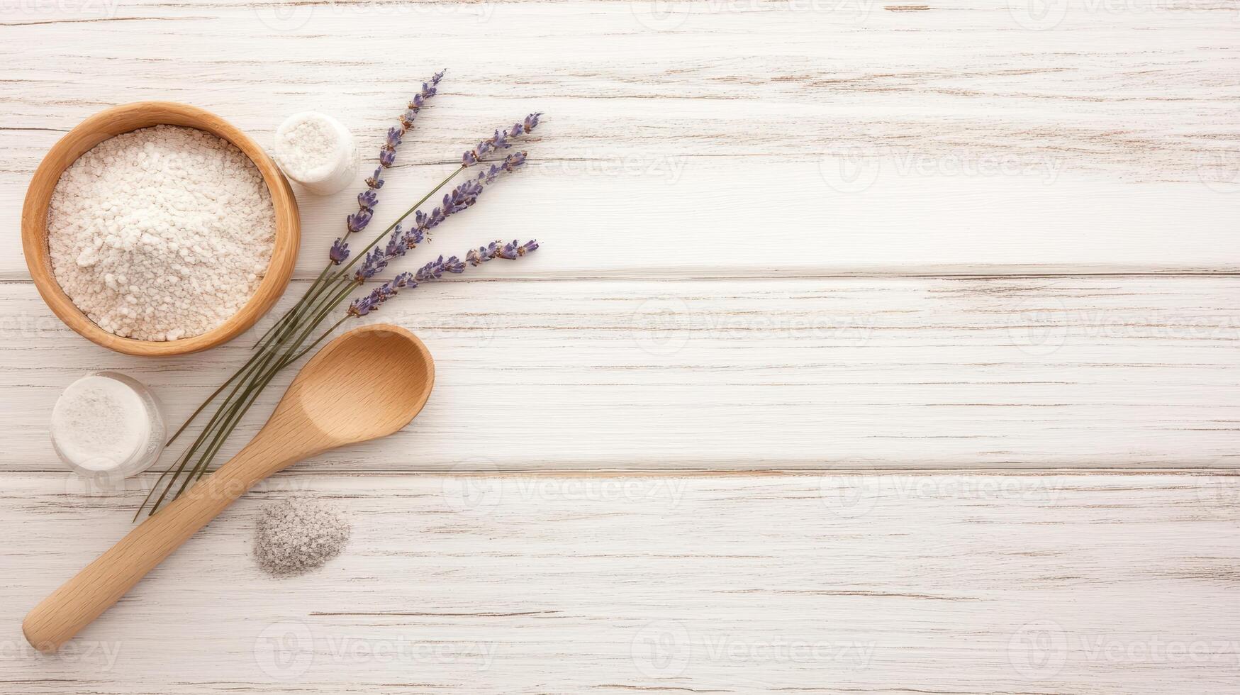 Wooden bowl with white powder and small jars beside lavender sprigs and spoon on light rustic wooden planks surface with copy space photo