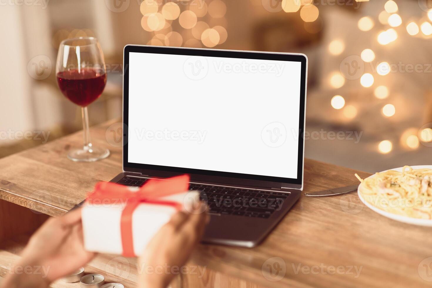 Virtual Party During Pandemic. Back over the shoulder view of young black woman having online call or date, lady showing present box with gifts to laptop with white blank empty screen for mockup photo