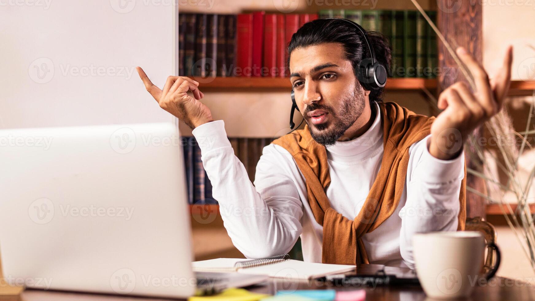 Indian Teacher Having Virtual Lesson Sitting At Laptop And Talking To Webcam Explaining Class Online Teaching Distantly At Home. E-Learning, E-Teaching And Distance Education photo