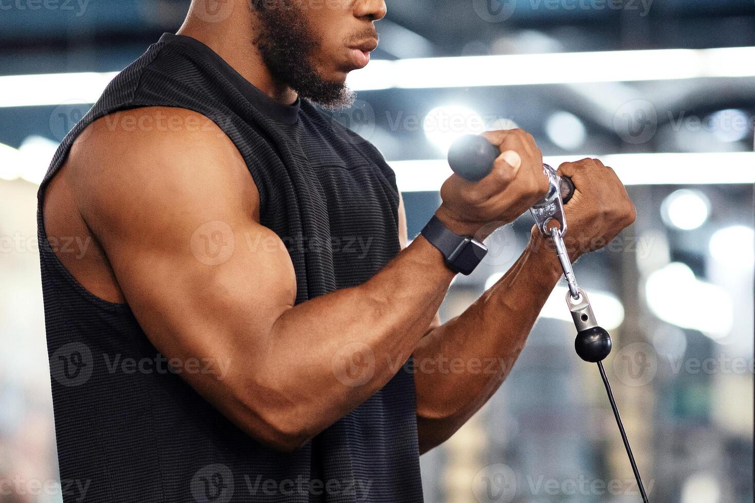 Concentrated black sportsman training muscles on block exerciser in gym, side view, copy space. Motivated african american bodybuilder having workout at modern gym, using peck deck machine photo