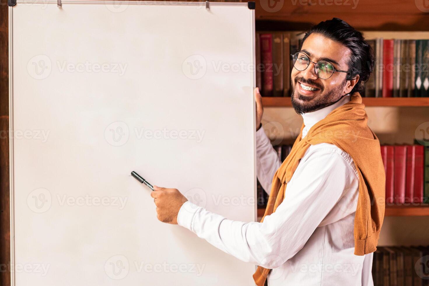 E-Teaching. Indian Teacher Man Posing Near Blackboard Having Online Class Of English Language Indoor, Smiling To Camera. Grammar Rules. E-Learning, Modern Education Concept photo