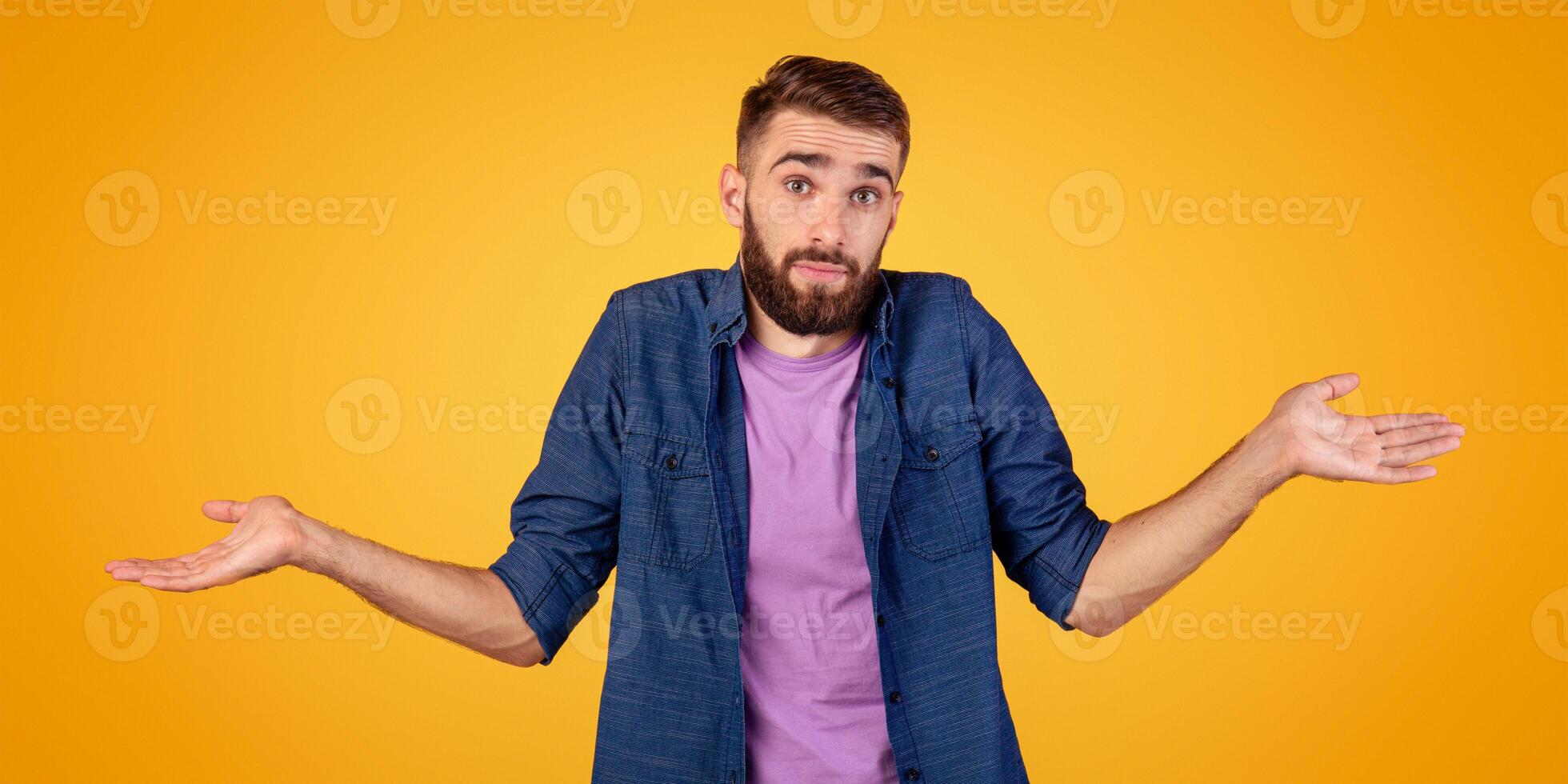 I don't know. Handsome Caucasian guy shrugging shoulders, feeling puzzled or uncertain on orange studio background. Confused millennial man expressing doubt, making difficult choice, panorama photo