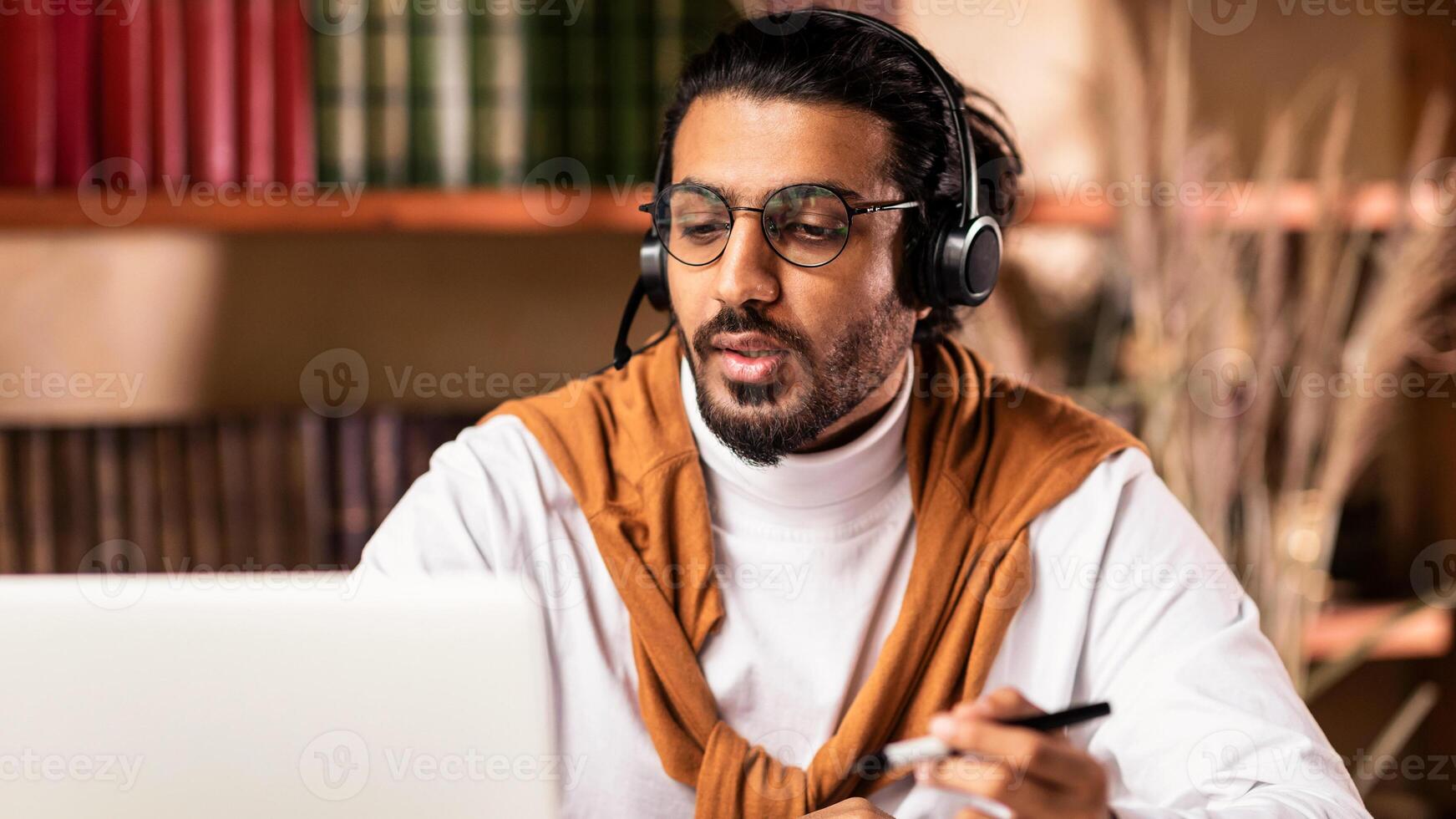 Indian Tutor At Laptop Making Call Teaching Students Online Having Webinar Distant Lecture At Home, Wearing Headphones. Distance Class, Remote Education, E-Teaching And Tutoring Concept photo