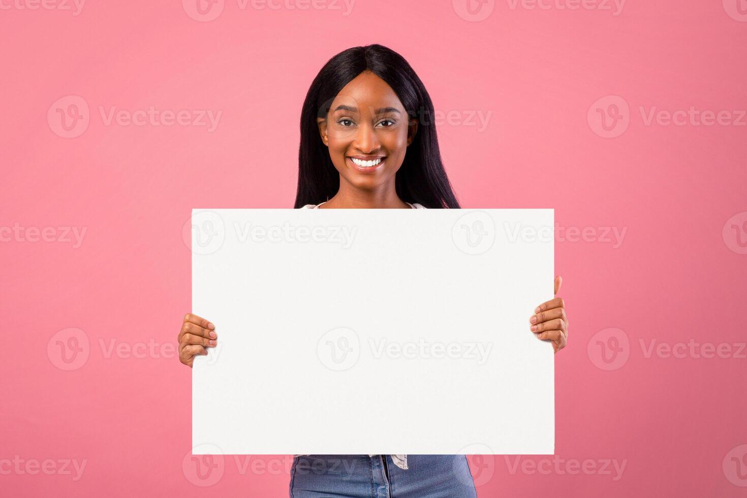 Beautiful African American lady with blank banner on pink studio background, mockup for your ad design. Lovely black woman showing empty poster, pomoting your brand, copy space photo