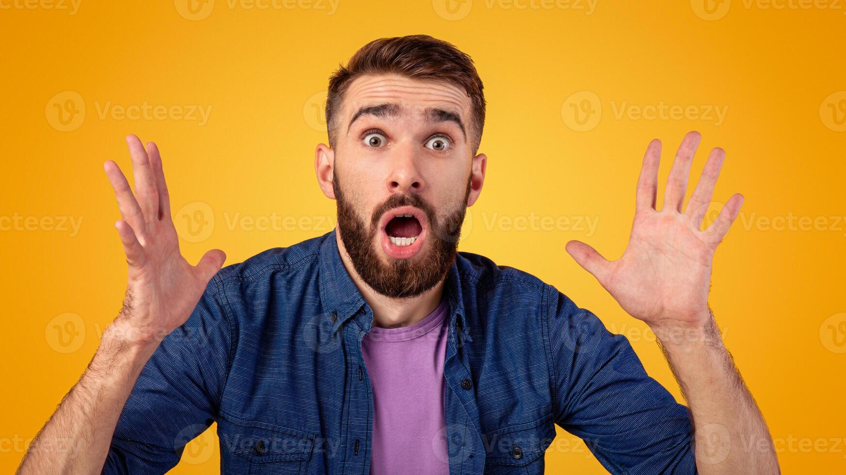 Human emotions and feelings concept. Portrait of shocked Caucasian man with open mouth looking at camera in amazement, making surprised gesture over orange studio background photo