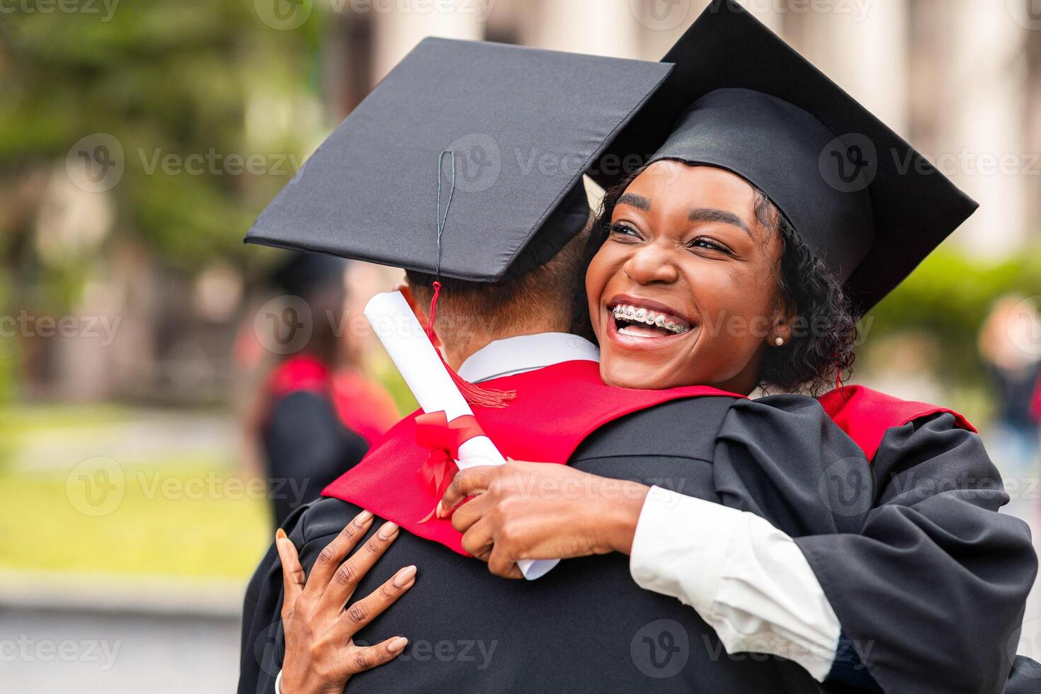 Congratulations. Happy african american couple students in graduation dresses and hats embracing, having ceremony at university campus, enjoying and celebrating graduation, closeup portrait photo