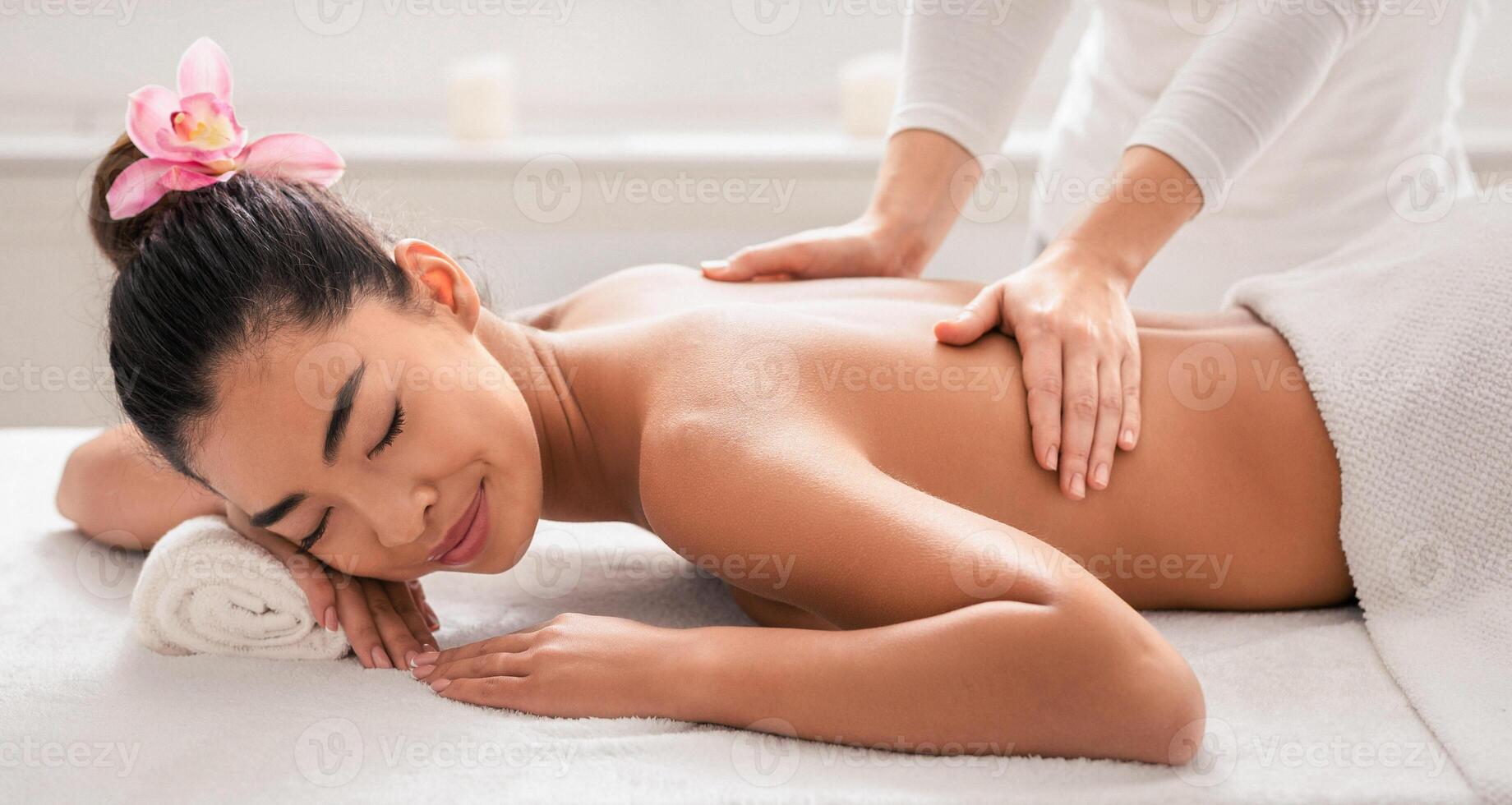 Relaxed asian woman receiving spa treatment from professional masseur in salon, getting back massage, lying on table with closed eyes, korean lady enjoying wellness day at beauty parlor, copy space photo