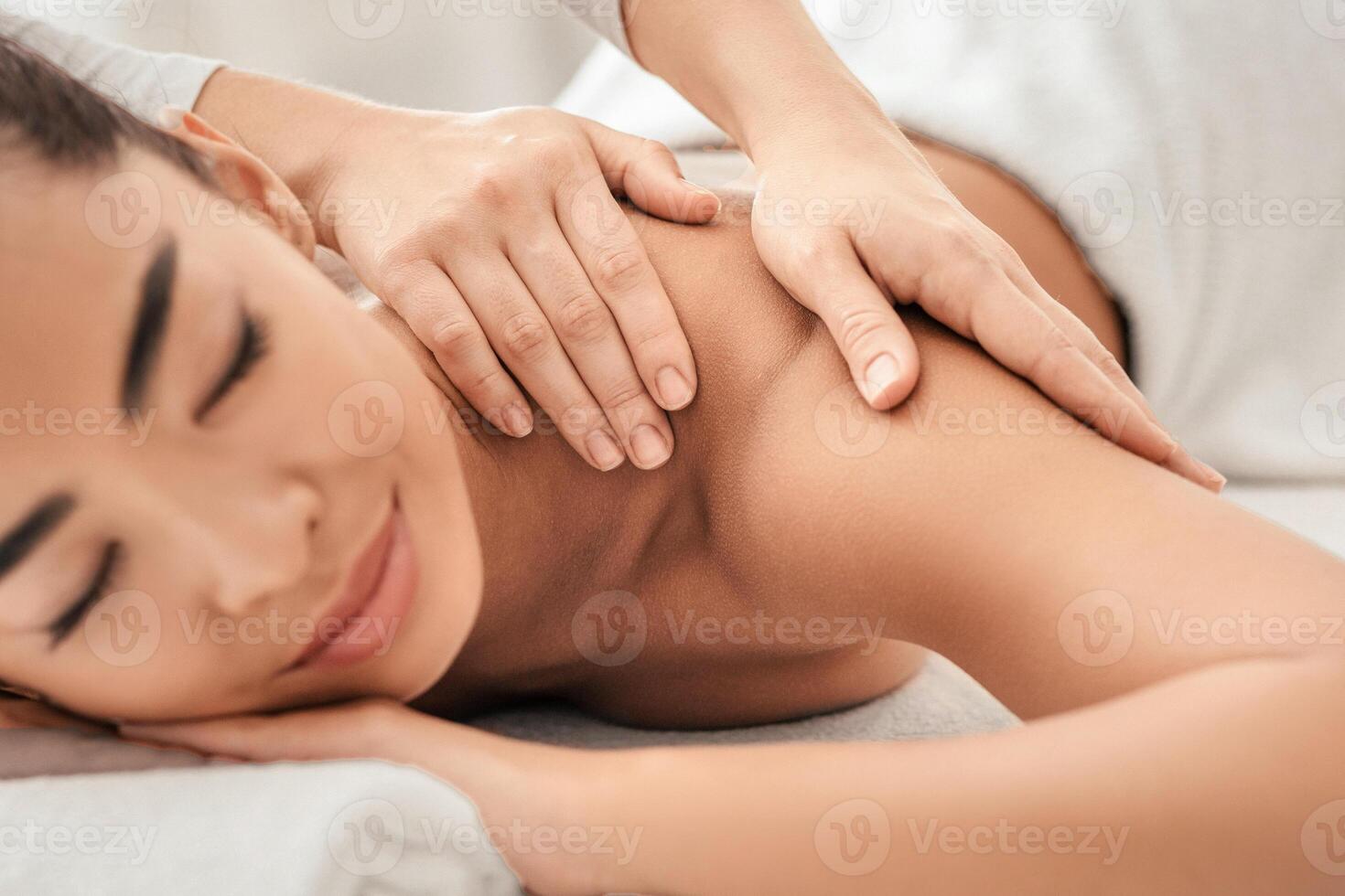 Closeup shot of young asian woman getting relaxing massage in spa salon. Professional therapist massaging shoulders of attractive korean lady during wellness treatment procedure, beauty concept photo