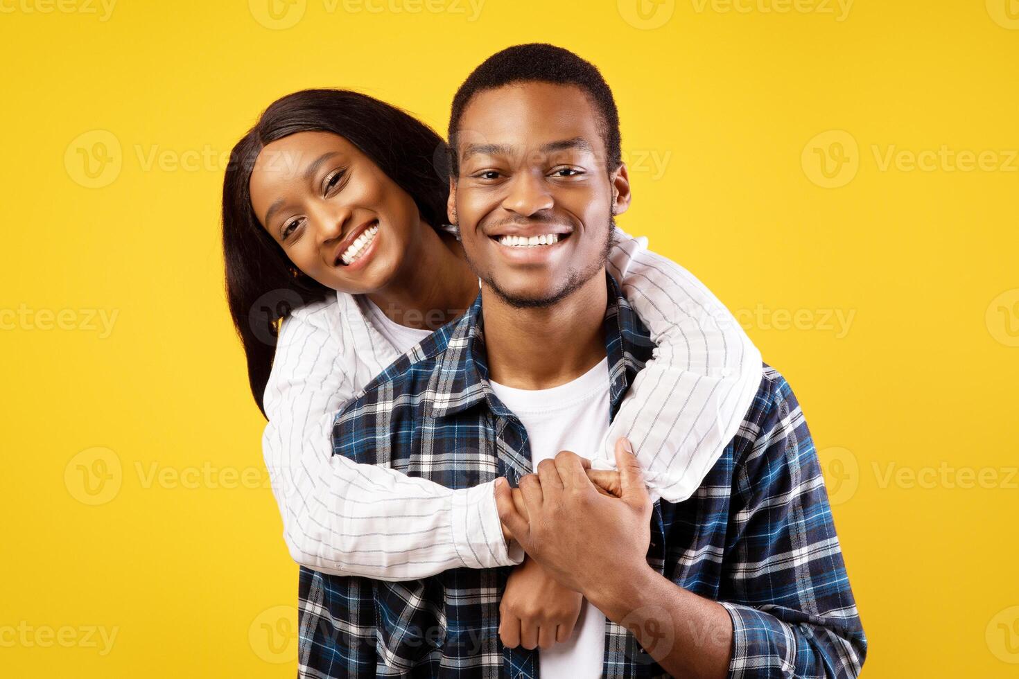 Meeting, love and date of young people. Smiling millennial african american couple in casual flirt, hugging and looking at camera, isolated on yellow background, studio shot, free space, cut out photo