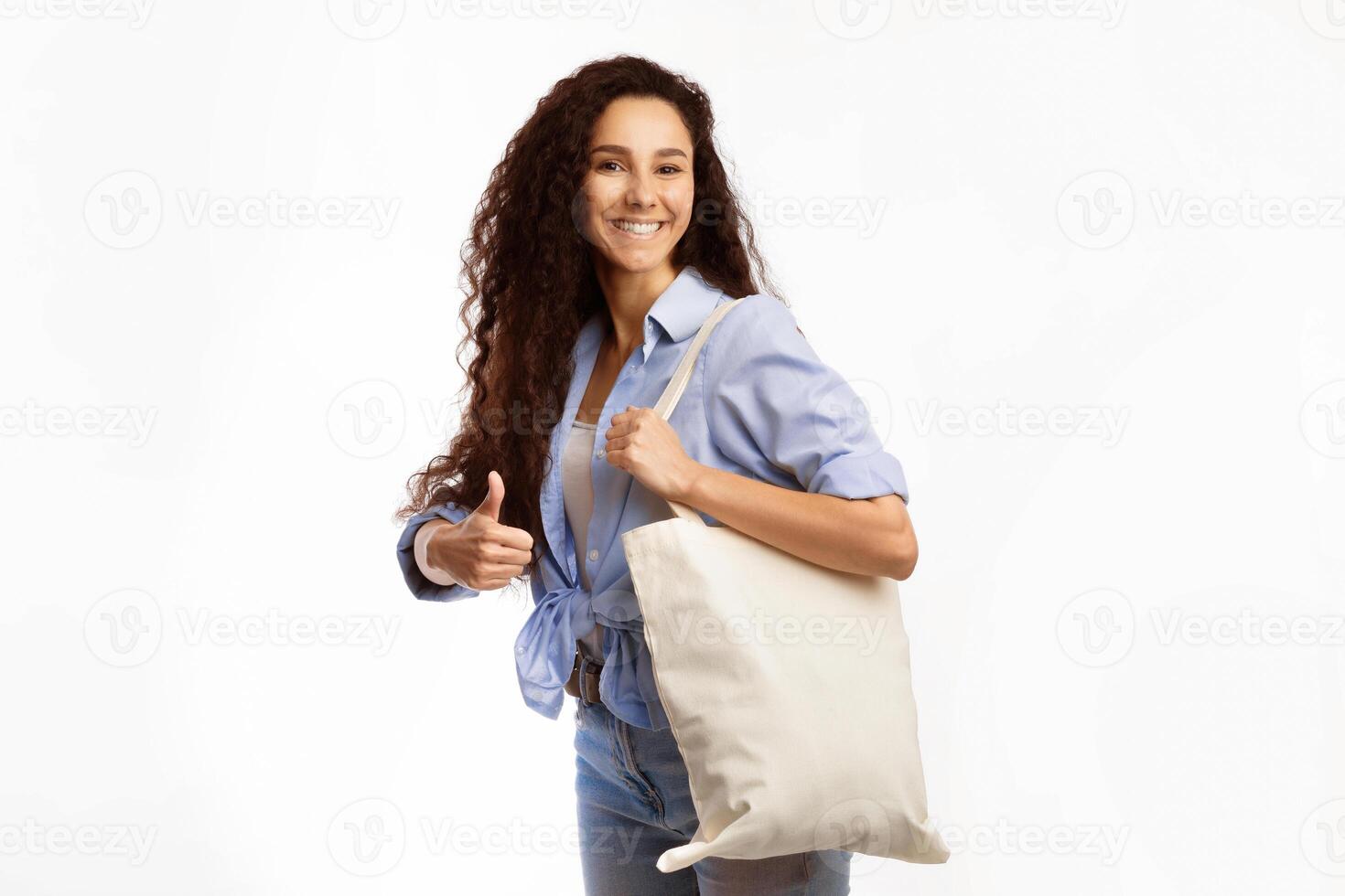 No Plastic. Happy Woman Carrying White Eco Shopper Bag And Gesturing Thumbs Up Standing On White Background In Studio. I Like Eco-Friendly Shopping And Lifestyle Concept photo
