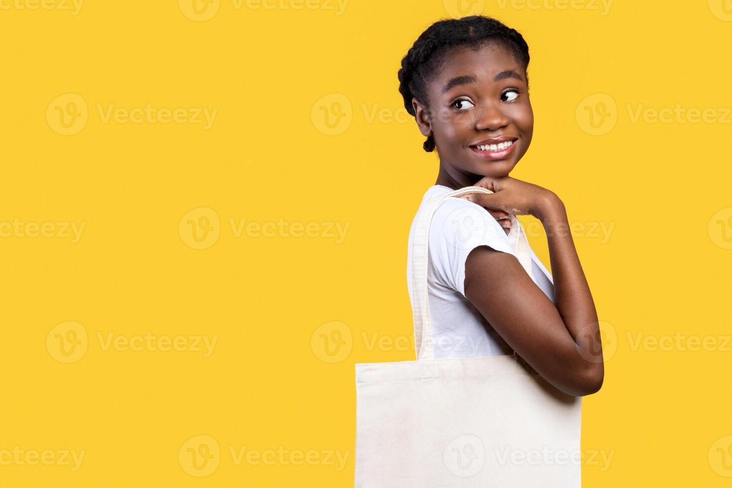 African American Woman Posing With White Eco Bag Standing Over Yellow Studio Background. Female Customer With Canvas Tote Shopper Handbag. Ecology, Stop Using Plastic Concept. Free Space For Text photo