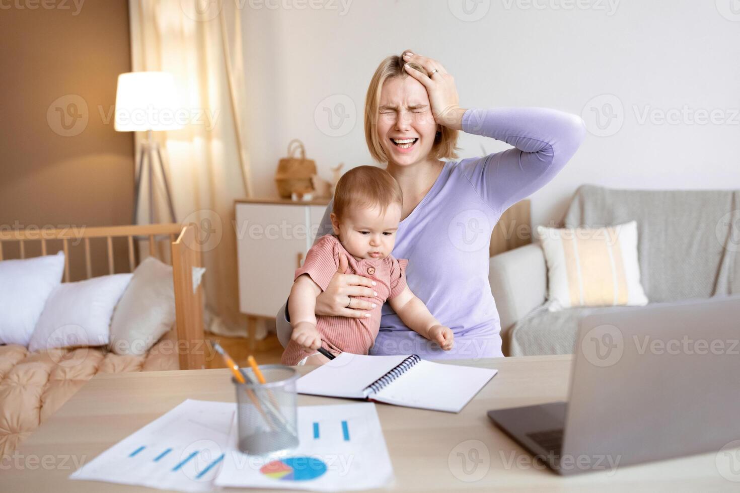 Nervous blonde woman young mother of toddler working from home, sitting in front of laptop, reading marketing reports, touching her head and screaming, holding baby on her lap, copy space photo