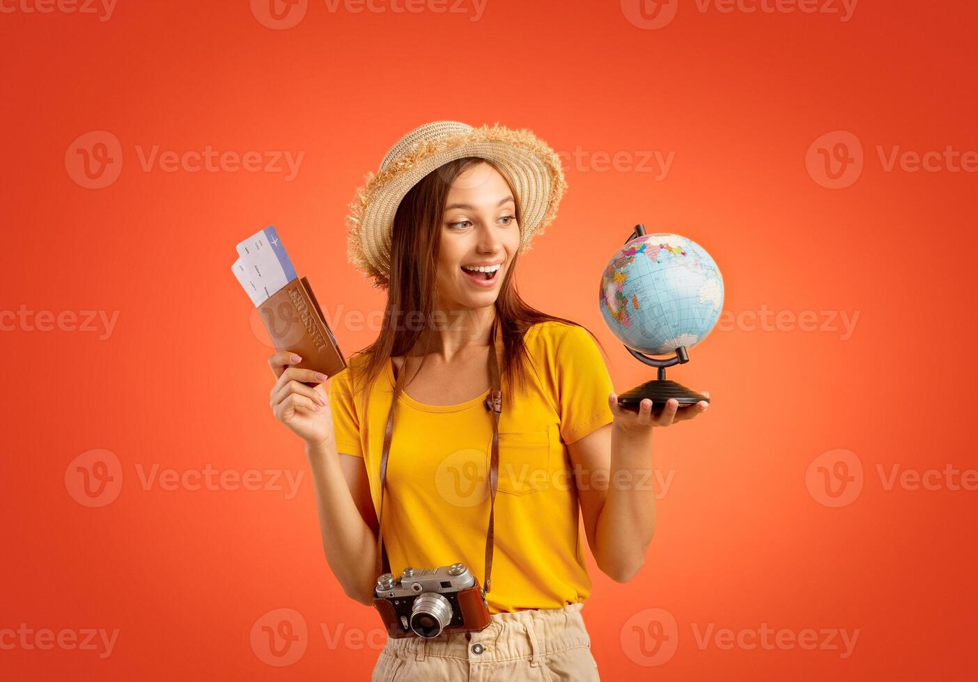 Exctited girl with passport, tickets, globe and camera over yellow studio background, going vacation photo