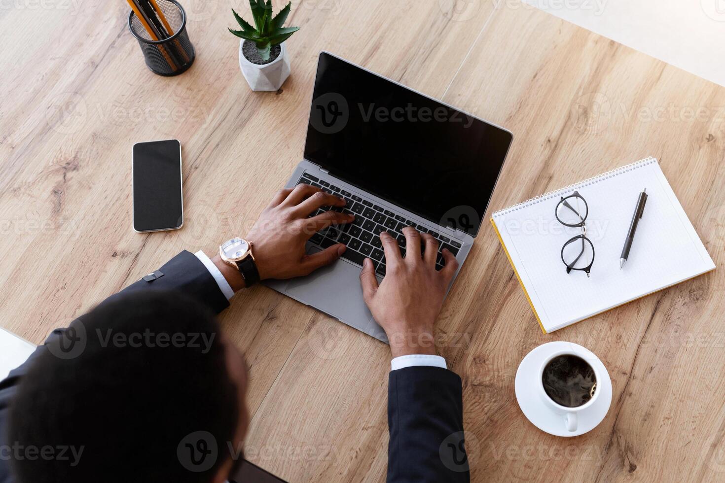 Top view of african american businessman typing on modern laptop with empty screen, black manager working online in his office, having online conference or call with business partners, mockup photo