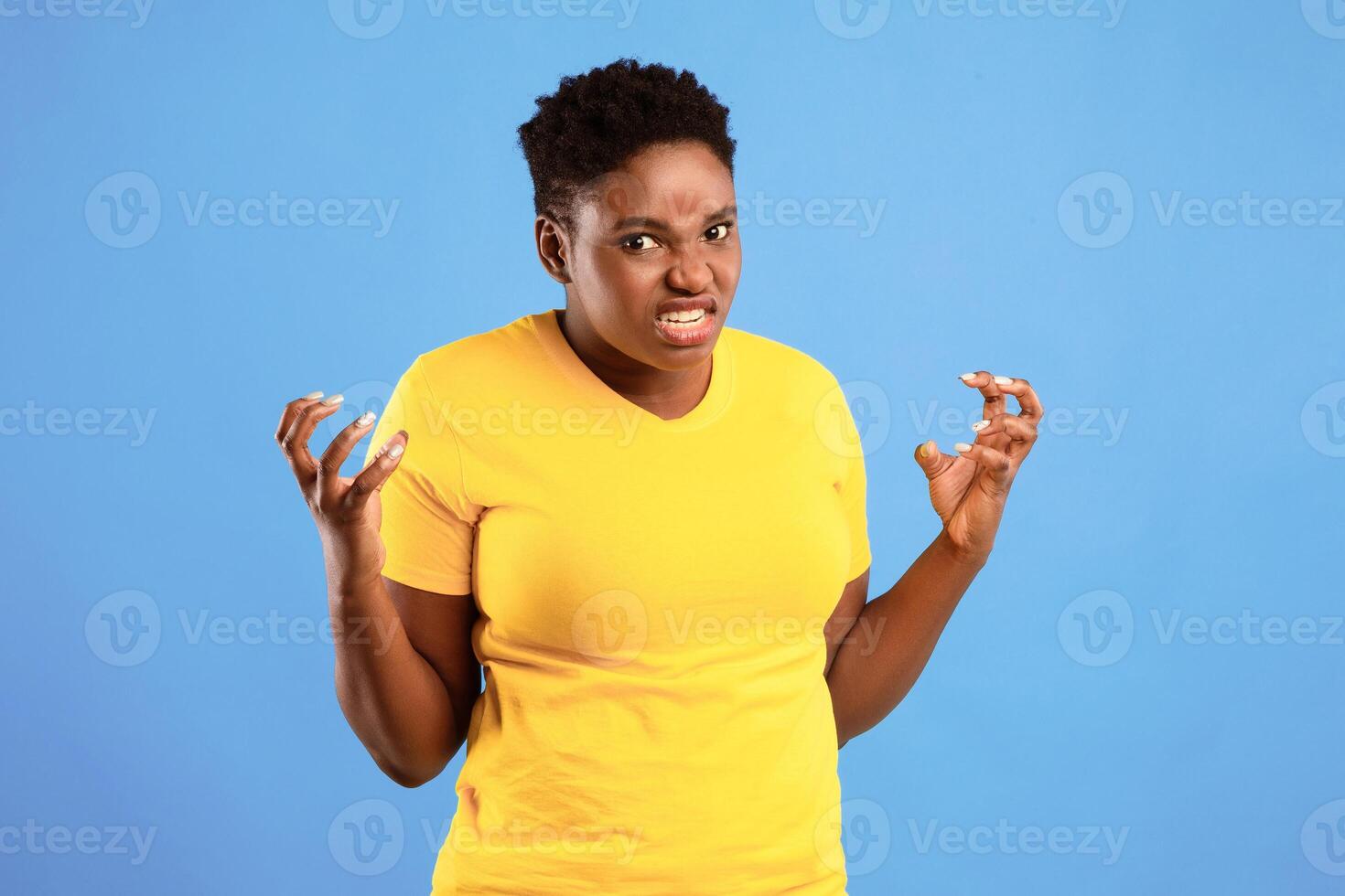 Mad African American Overweight Woman Freaking Out Looking Angrily At Camera Posing Standing Over Blue Background In Studio. Negative Emotion, Madness, Anger And Stress Concept photo