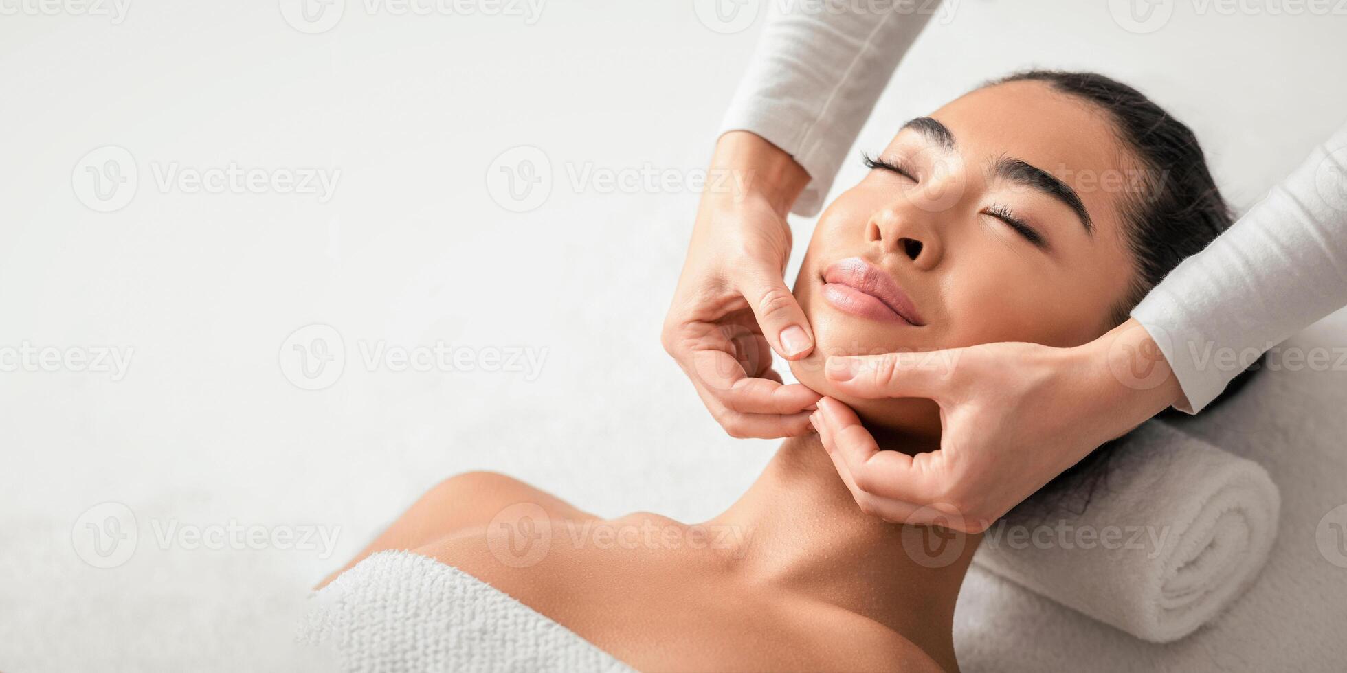 Face Lifting Massage. Young Korean Woman Getting Beauty Treatments By Professional Masseur At Cosmetology Cabinet, Relaxed Asian Female Enjoying Wellness Day At Spa Salon, Closeup Shot photo