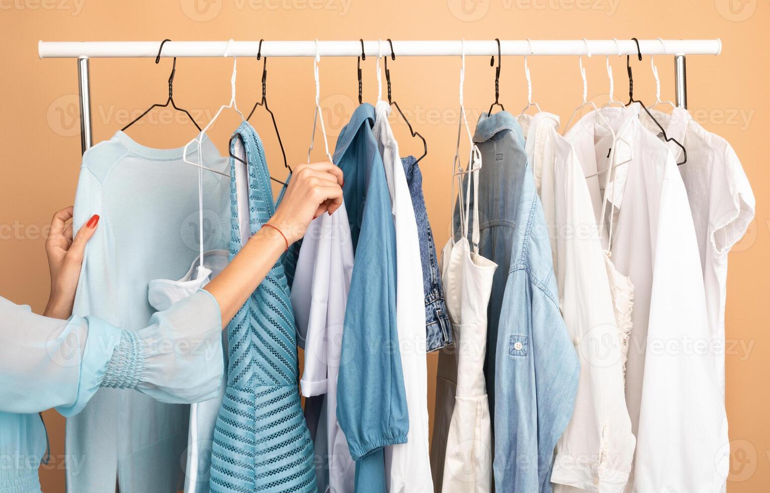 New Collection. Unrecognizable young woman shopping in fashion mall, choosing new clothes, looking through hangers with different casual colorful garments on clothing rail, closeup of hands photo