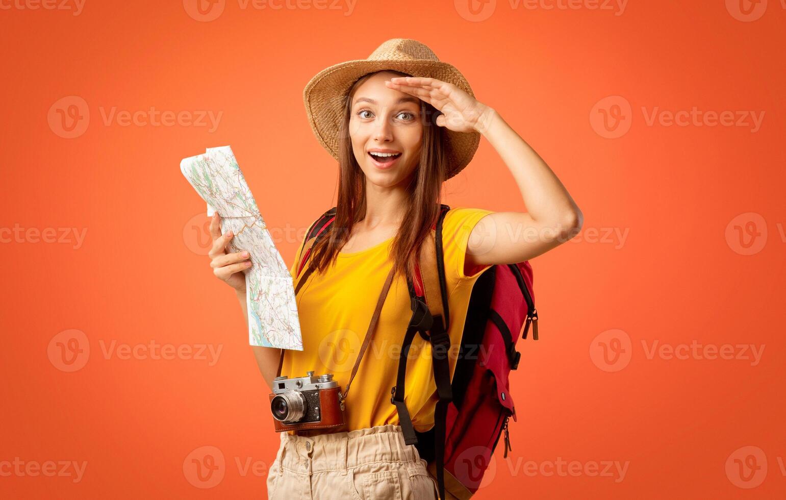 Amazed girl hiker with map doing sightseeing, yellow background photo