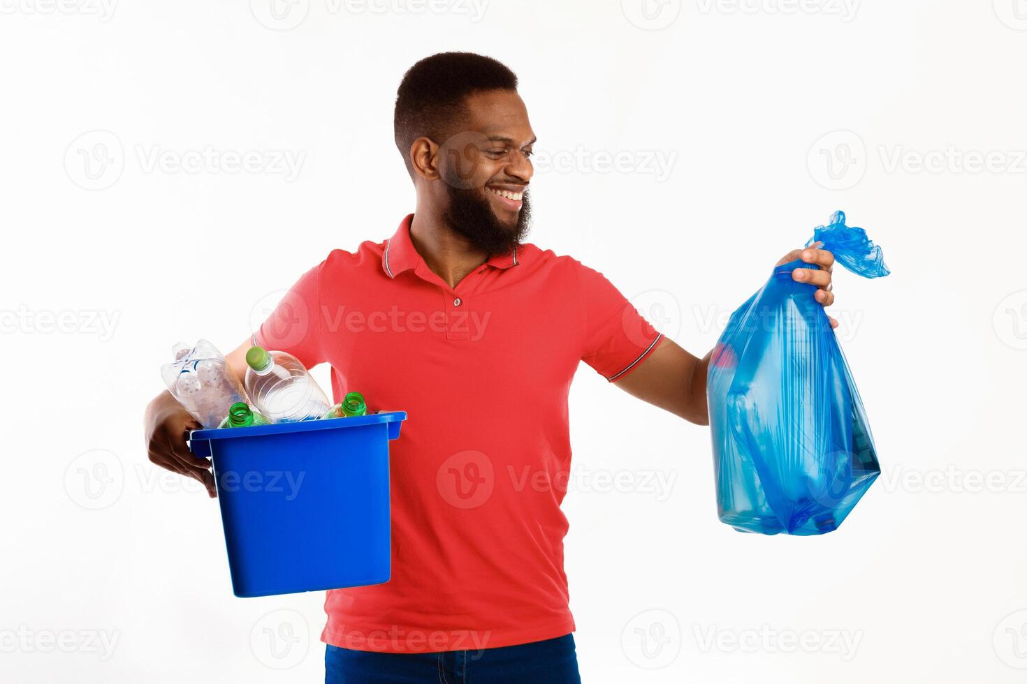 African American Millennial Man Holding Garbage Bag And Box With Recycle Symbol And Wasted Plastic Standing In Studio Over White Background. Sort Your Waste Concept photo