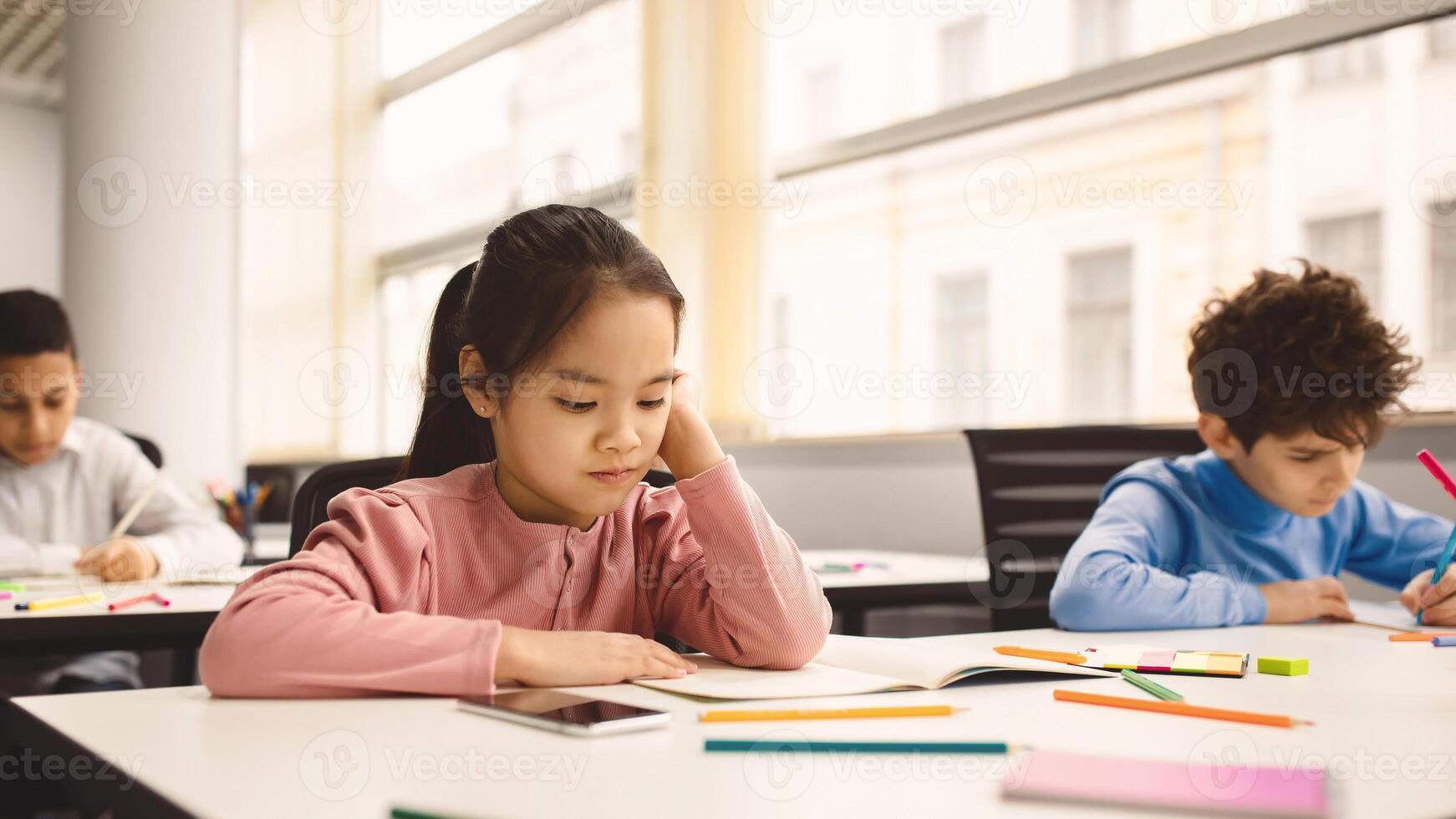 Learning Concept. Portrait Of Concentrated Japanese Schoolgirl Doing Homework Reading Book Or Notes In Her Copybook Sitting At Desk In Modern Classroom, Writing Test Thinking About Question, Banner photo