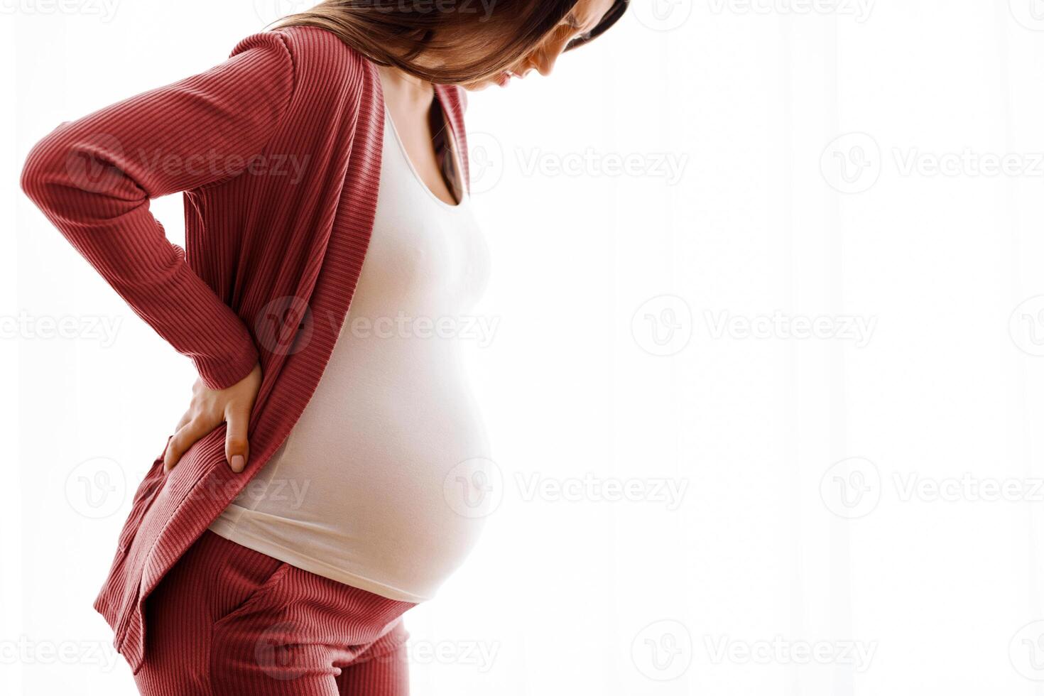 Pregnancy Backache. Closeup Shot Of Young Pregnant Woman Suffering Lower Back Pain, Millennial Expectant Lady Feeling Unwell While Standing Near Window At Home, Side View With Copy Space photo