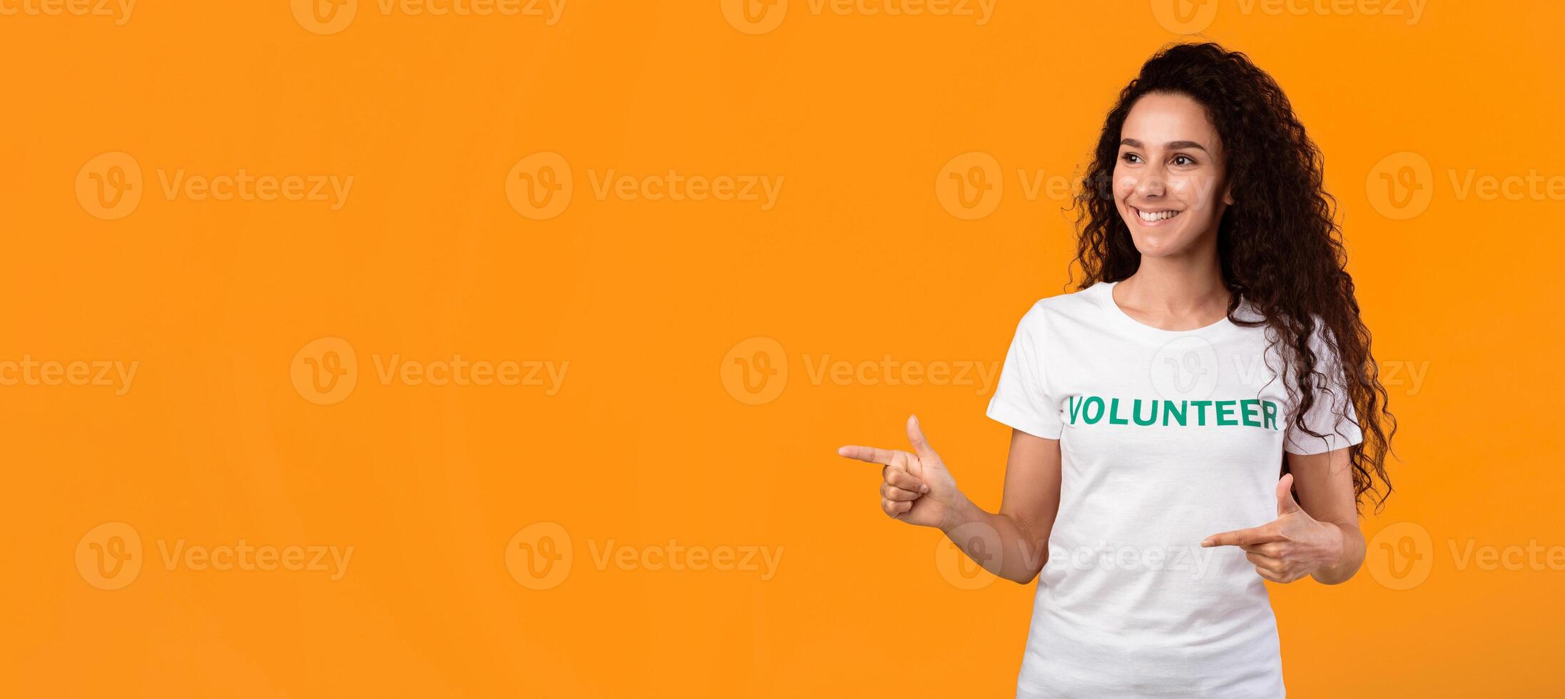 Look There. Female Volunteer Pointing Fingers Aside Showing Copy Space Standing Over Yellow Studio Background. Activist Advertising Volunteering Event Or Offer. Panorama photo